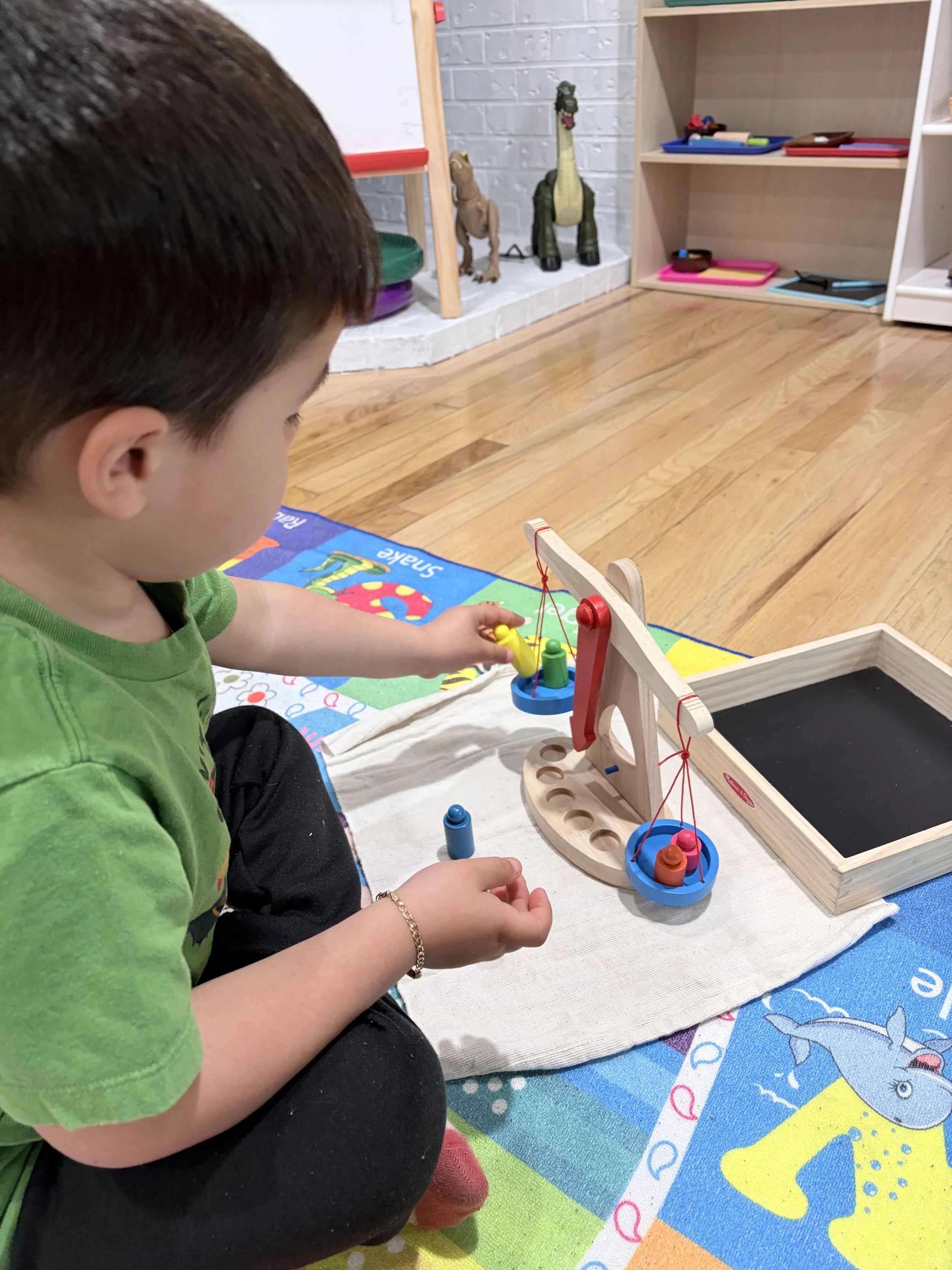 A young child playing with a wooden fishing game on a colorful children's play mat indoors.
