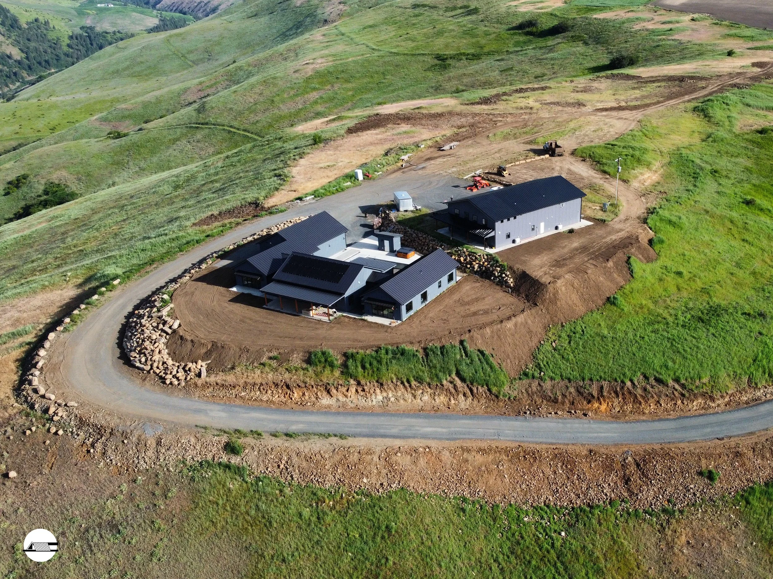 Construction site with a finished shop and house under construction with views over hills
