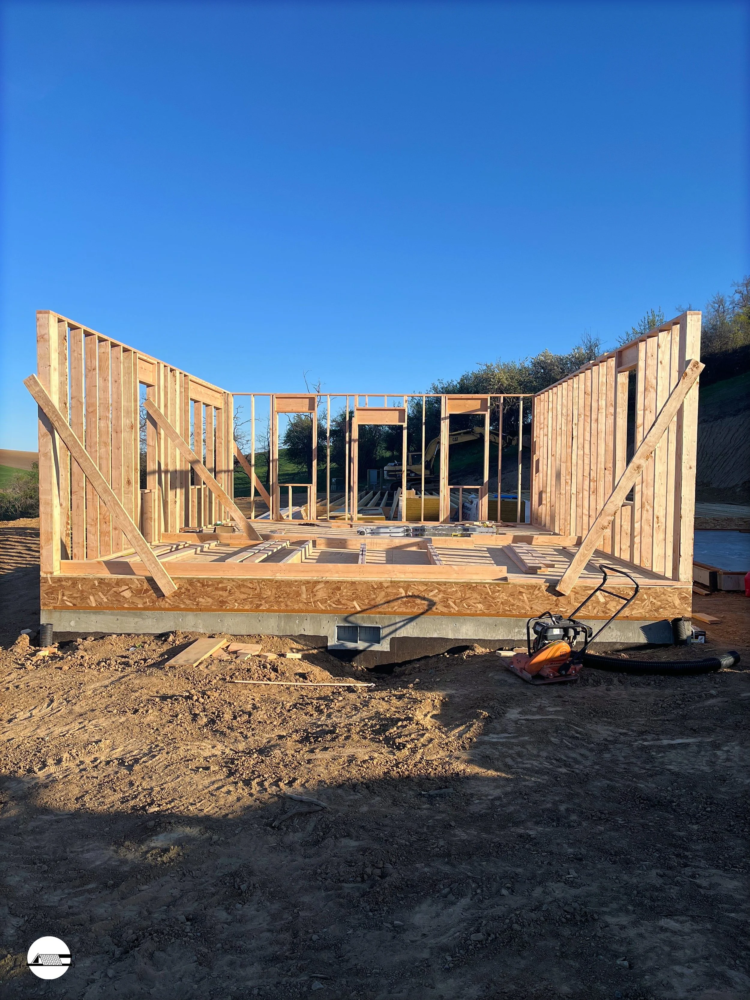 Construction site with wooden frame of a house, blue sky, and sunlight