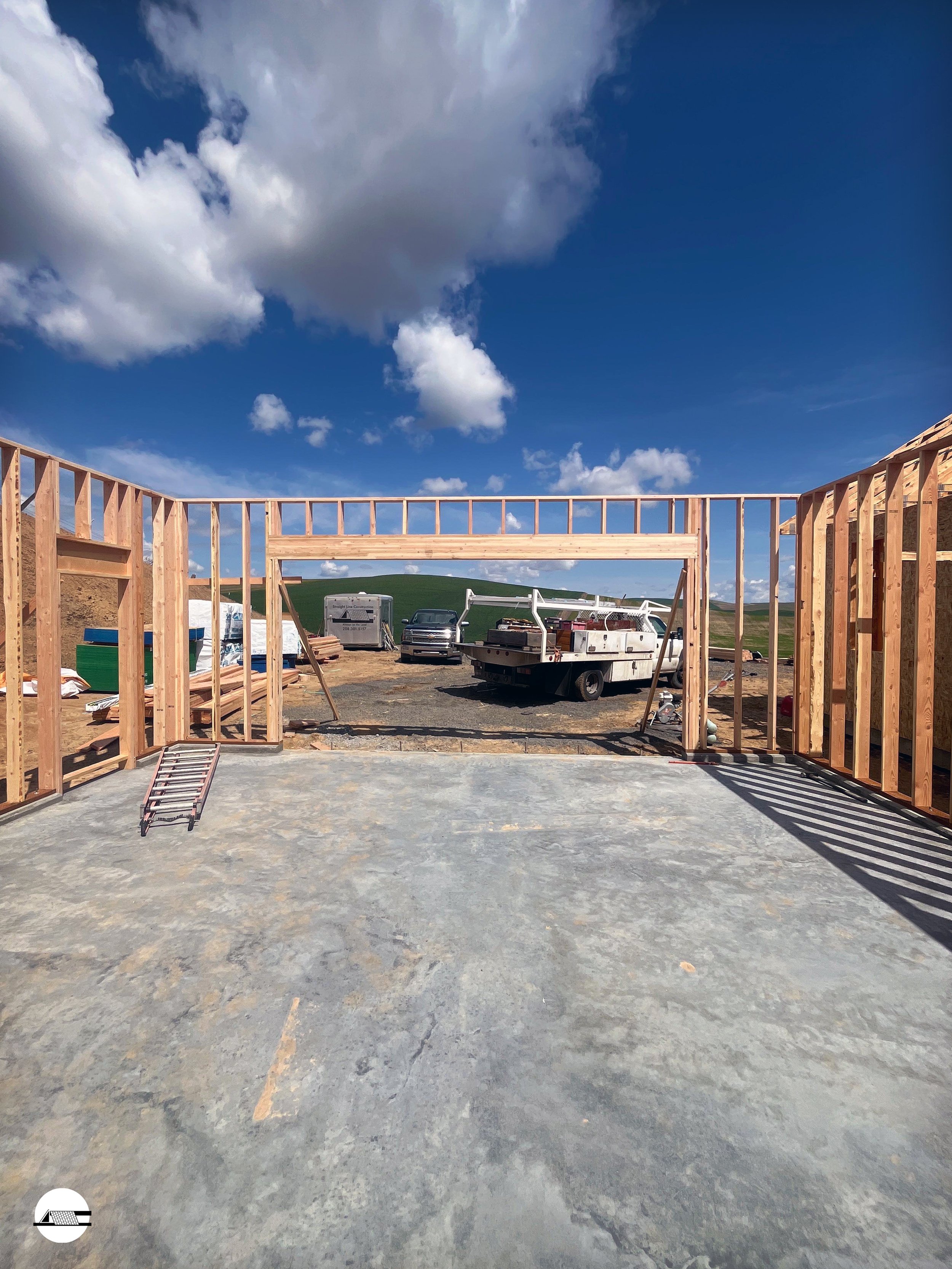 Construction site with wooden framing and construction equipment under a cloudy blue sky.