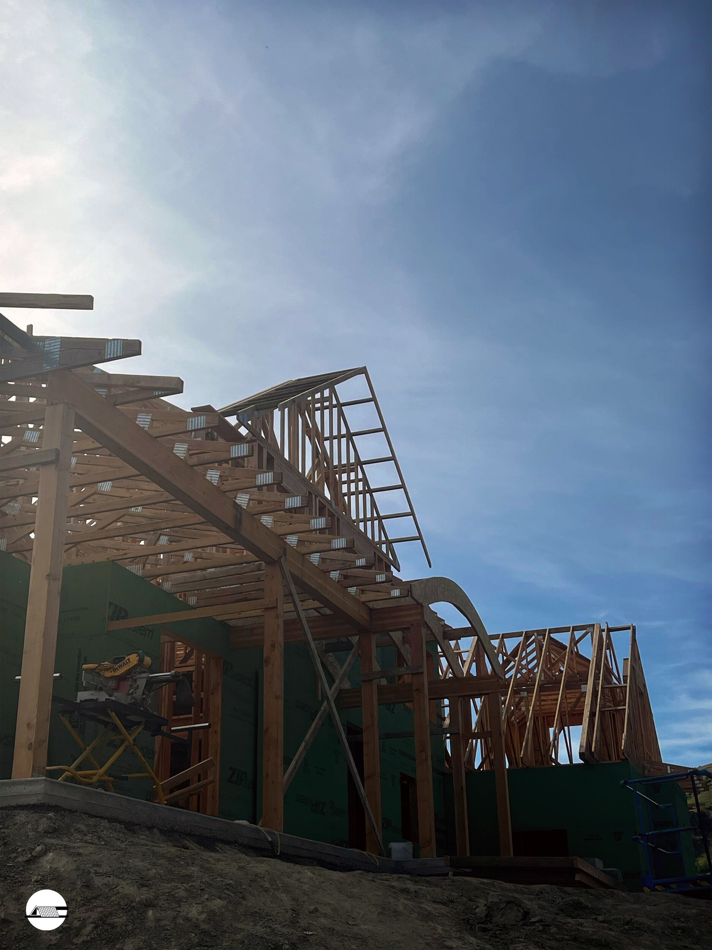 Wooden framing of a house under construction against a clear sky.