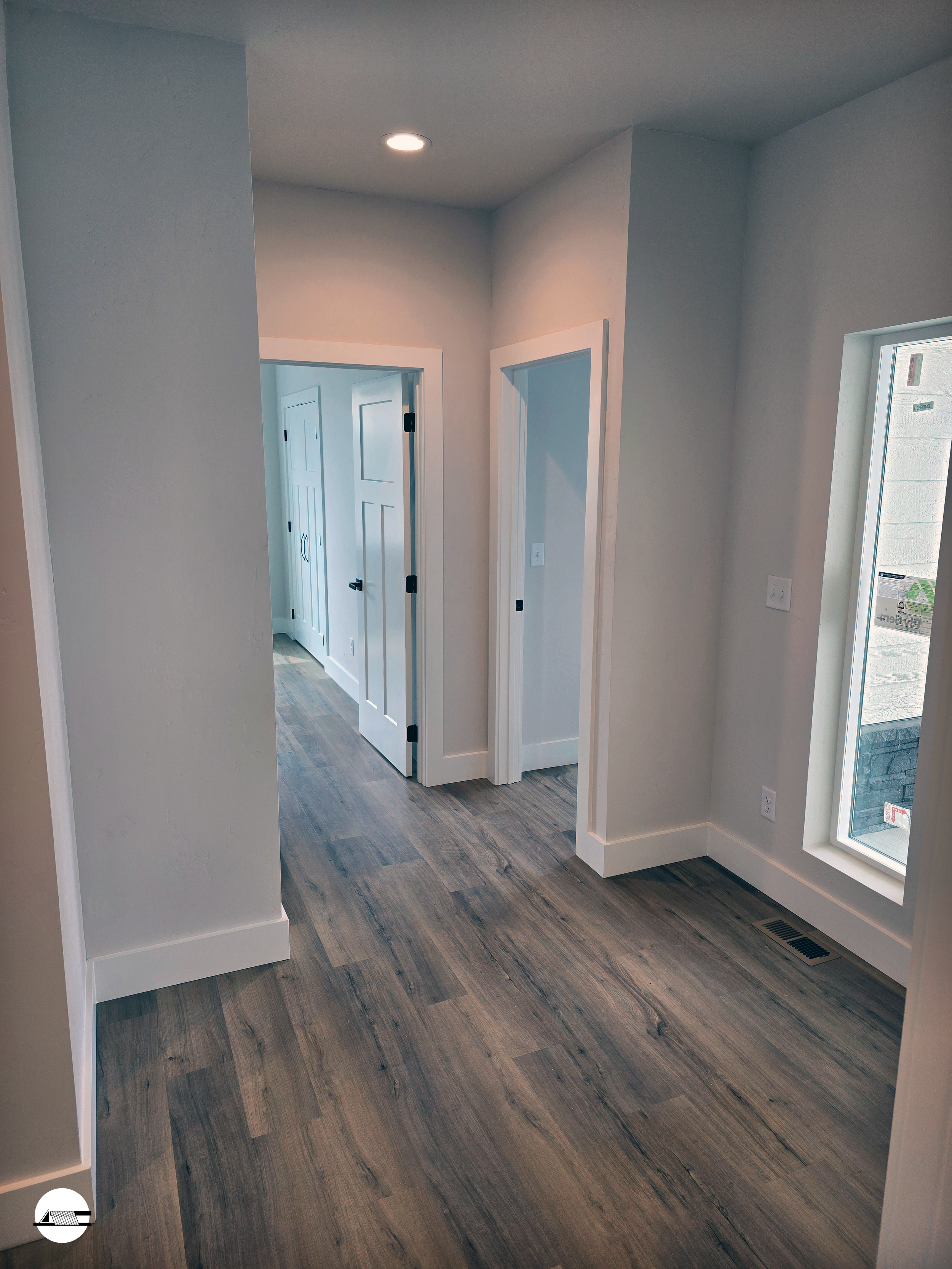 Interior of a modern house with light-colored walls, wood flooring, and doorways leading to different rooms.