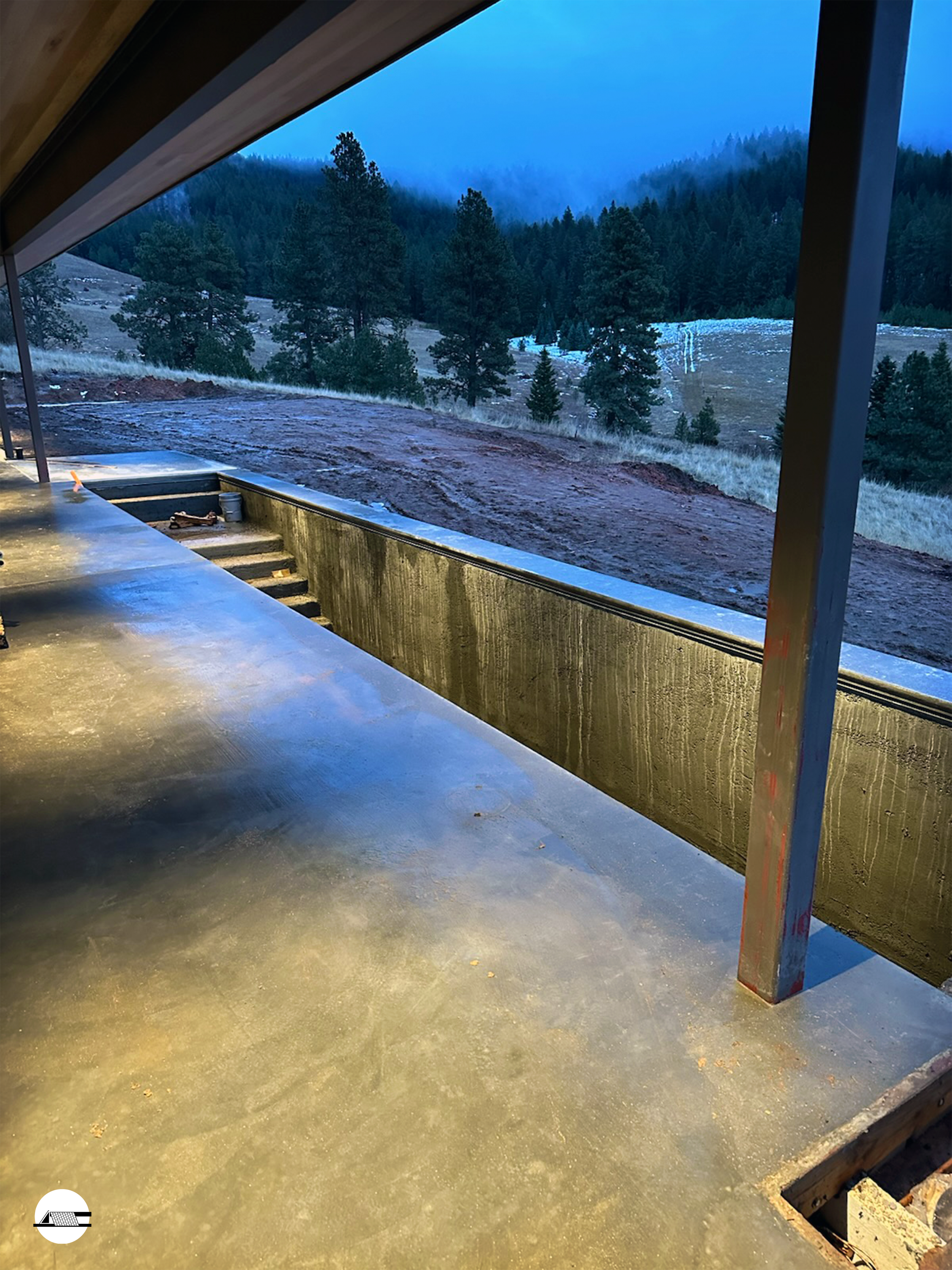 Concrete patio under construction with a view of a misty, forested mountain landscape in the background.