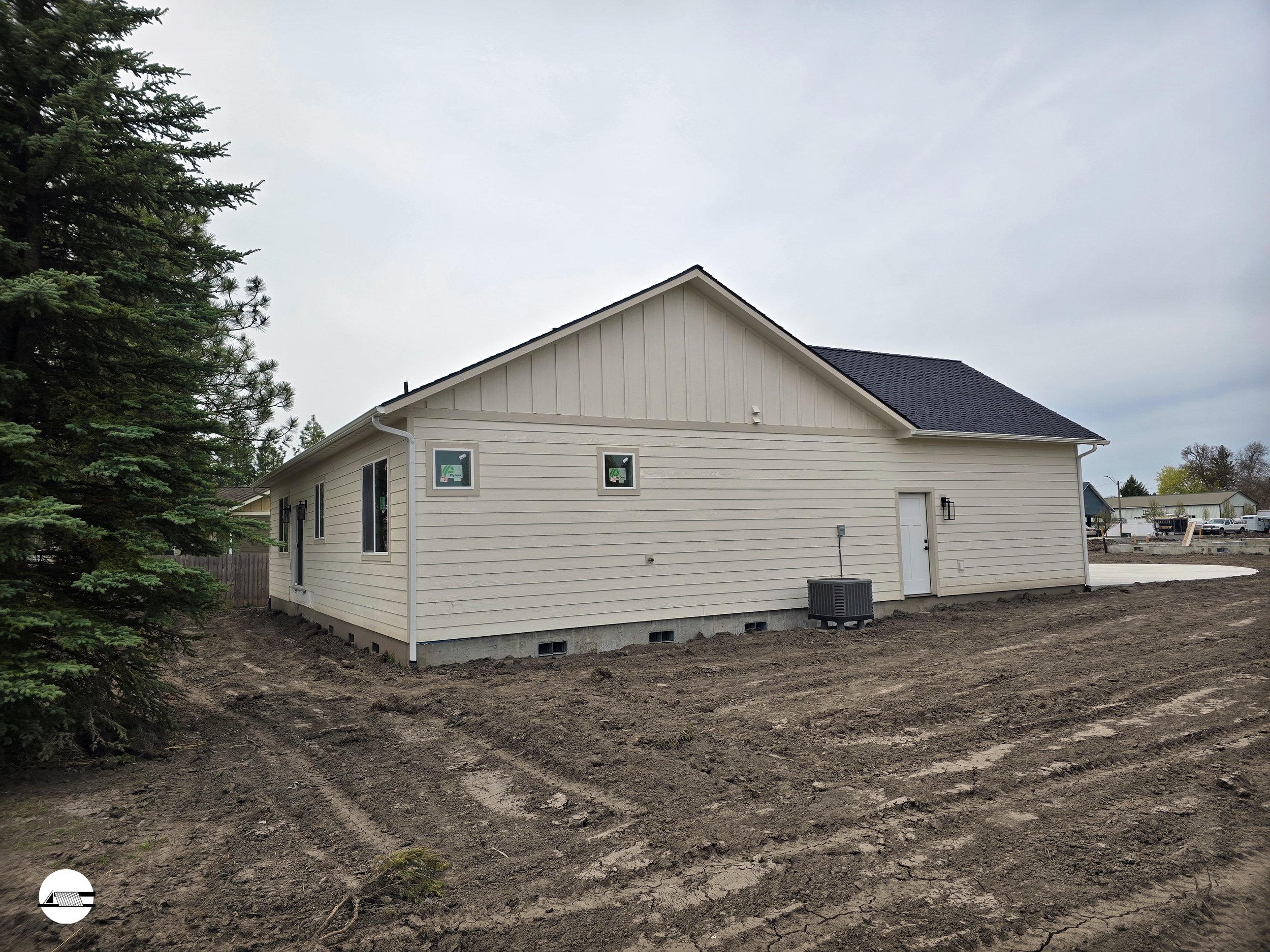 Behind a house, there is a large area of uneven dirt and soil, indicating ongoing landscaping or construction work.