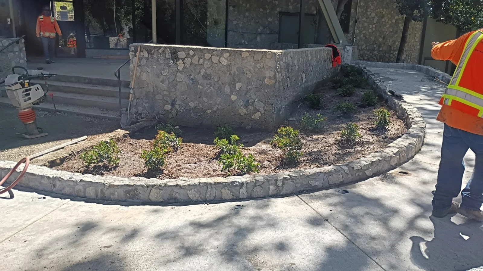 Lodge entrance with a curved concrete walkway and stone-bordered planting bed.