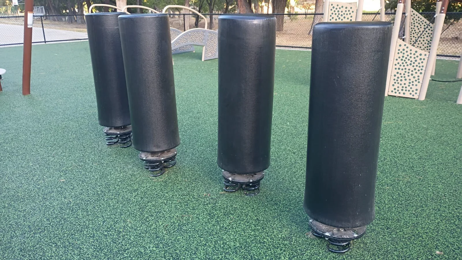Spring-mounted cylindrical obstacles with climbing equipment behind them.