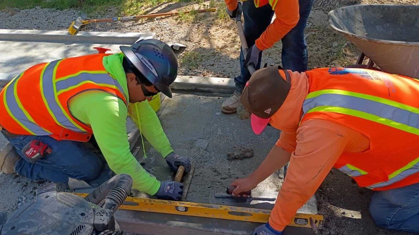 Crew members finishing concrete during obstacle course construction.