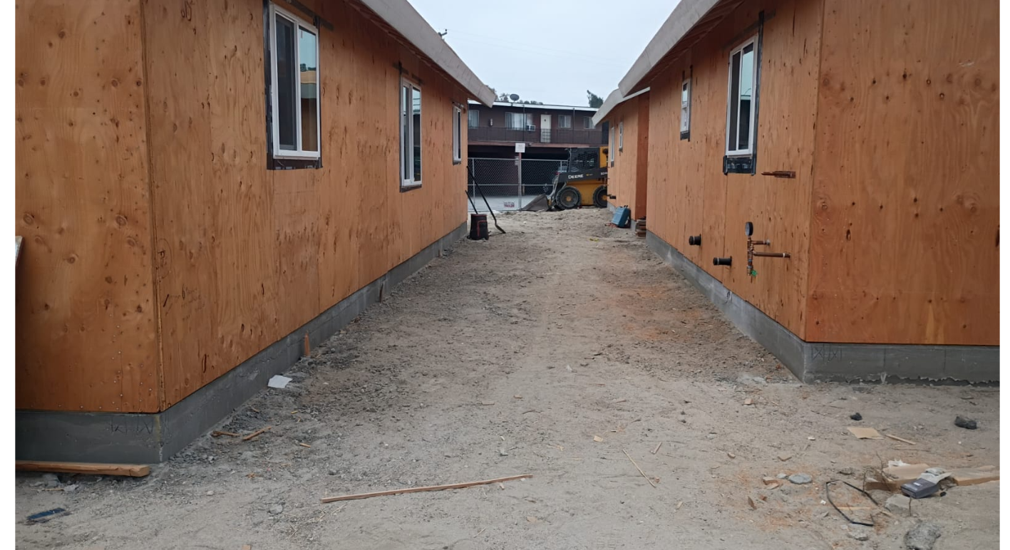 Passage between newly framed buildings with wall sheathing and windows