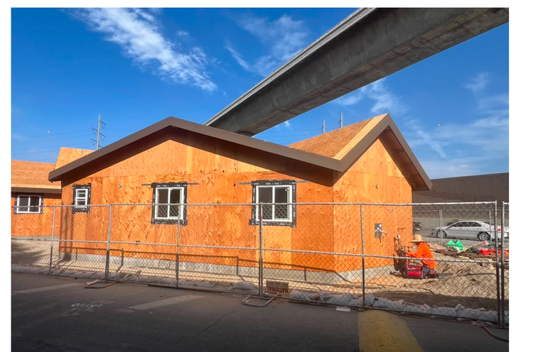 Multifamily building exterior with plywood sheathing, installed windows and gabled roofs