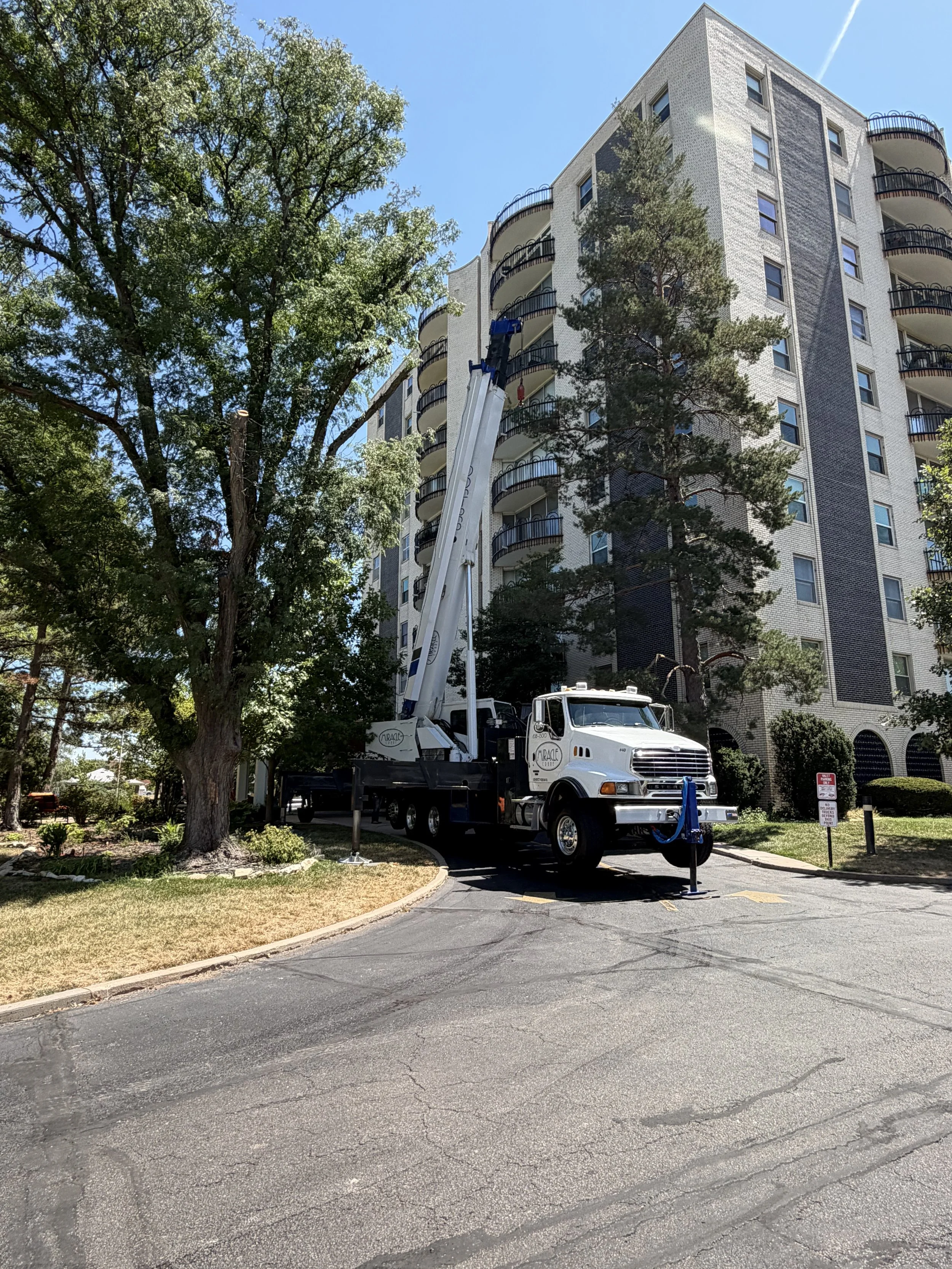 Miracle Crane truck-mounted crane set up beside a multi-story building for a high-reach lift in Wichita, Kansas.