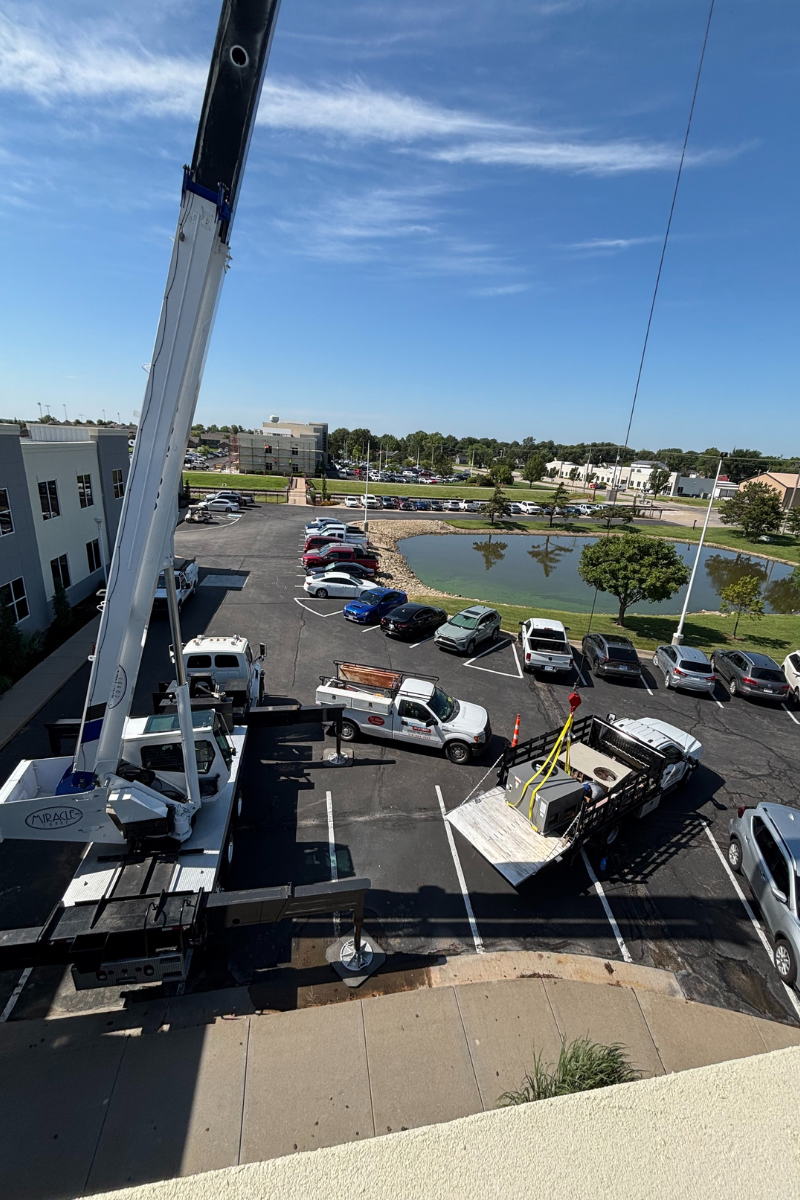 Crane and crew staging HVAC unit before rooftop lift in Wichita Kansas
