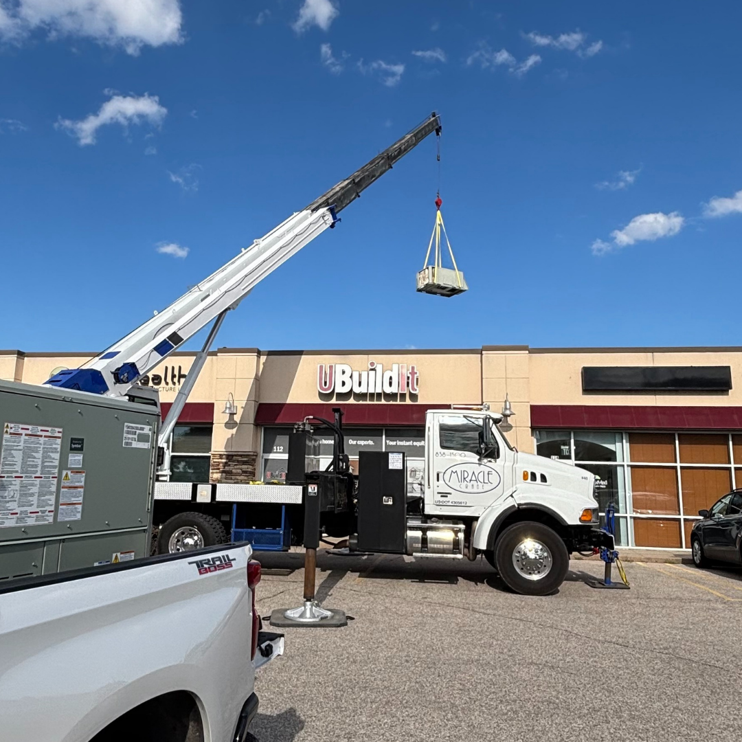 Mobile crane lifting rooftop HVAC unit onto commercial building in Wichita Kansas