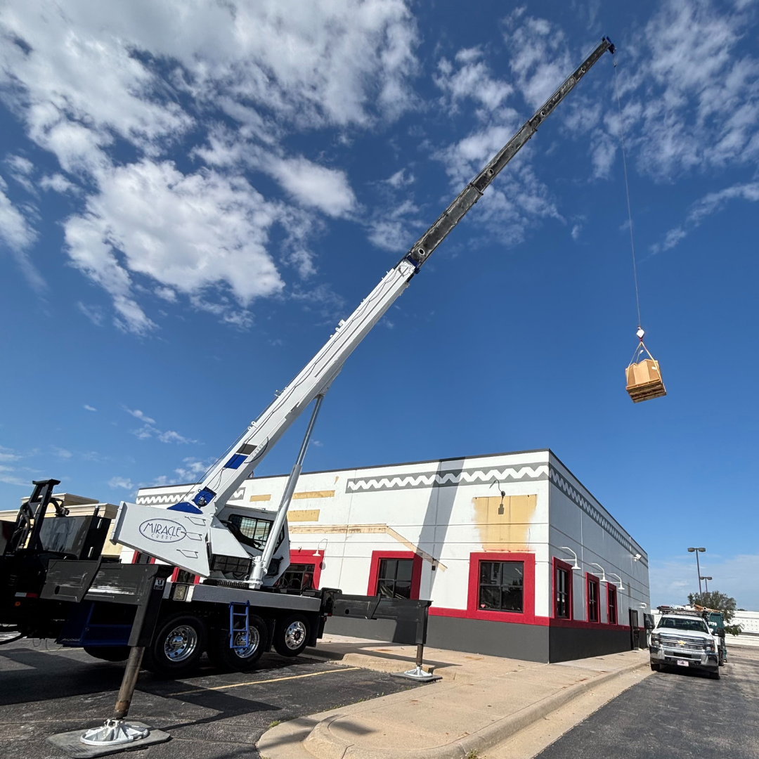 Mobile crane lifting hvac equipment next to restaurant building in Wichita Kansas