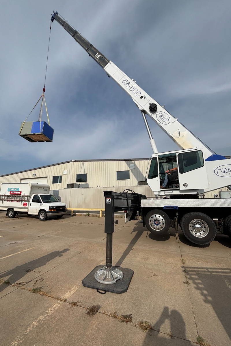 Mobile crane lifting rooftop HVAC unit at commercial job site in Wichita Kansas