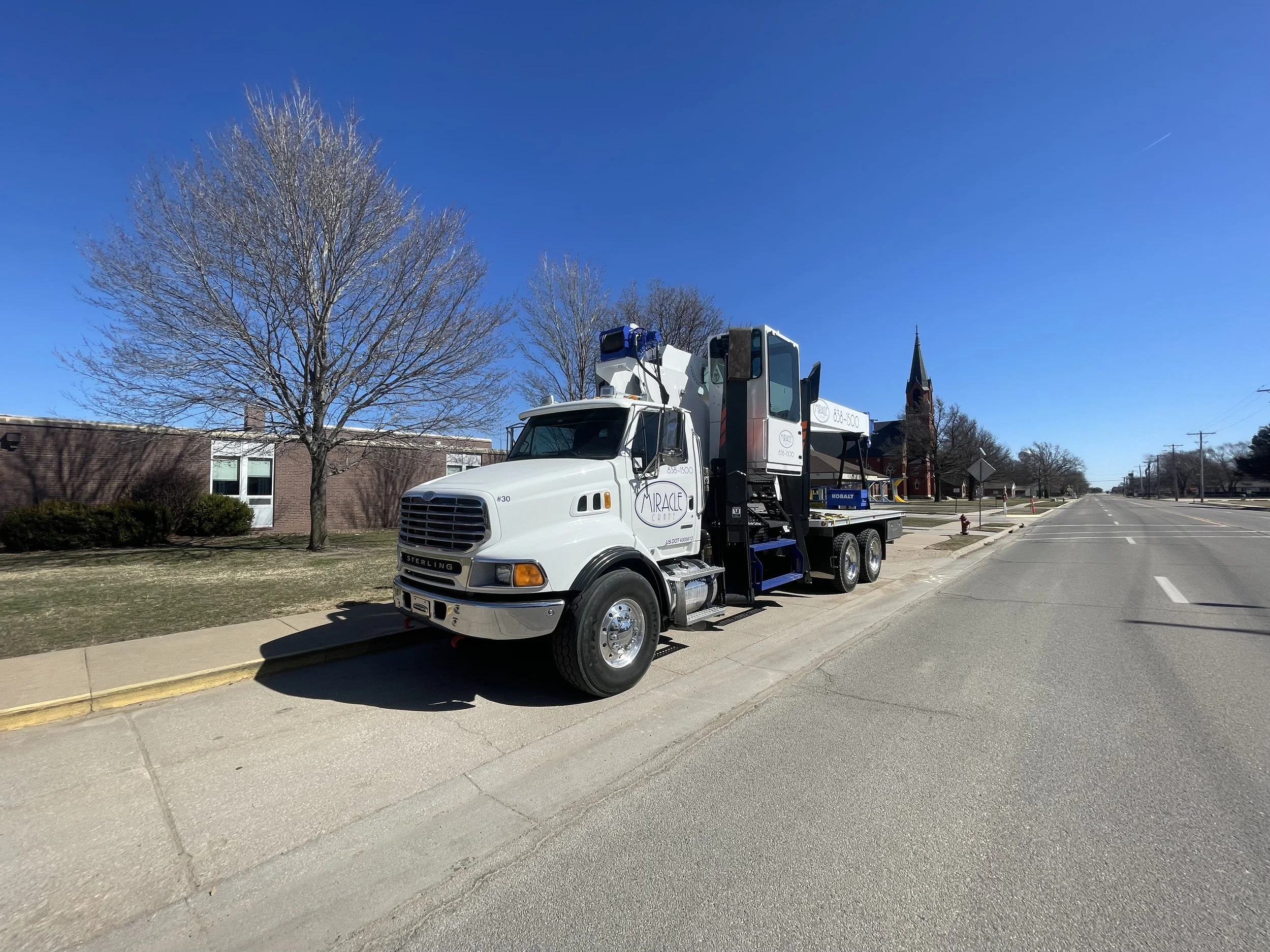 Miracle Crane truck with mounted crane parked along a street in Colwich, Kansas on a clear day