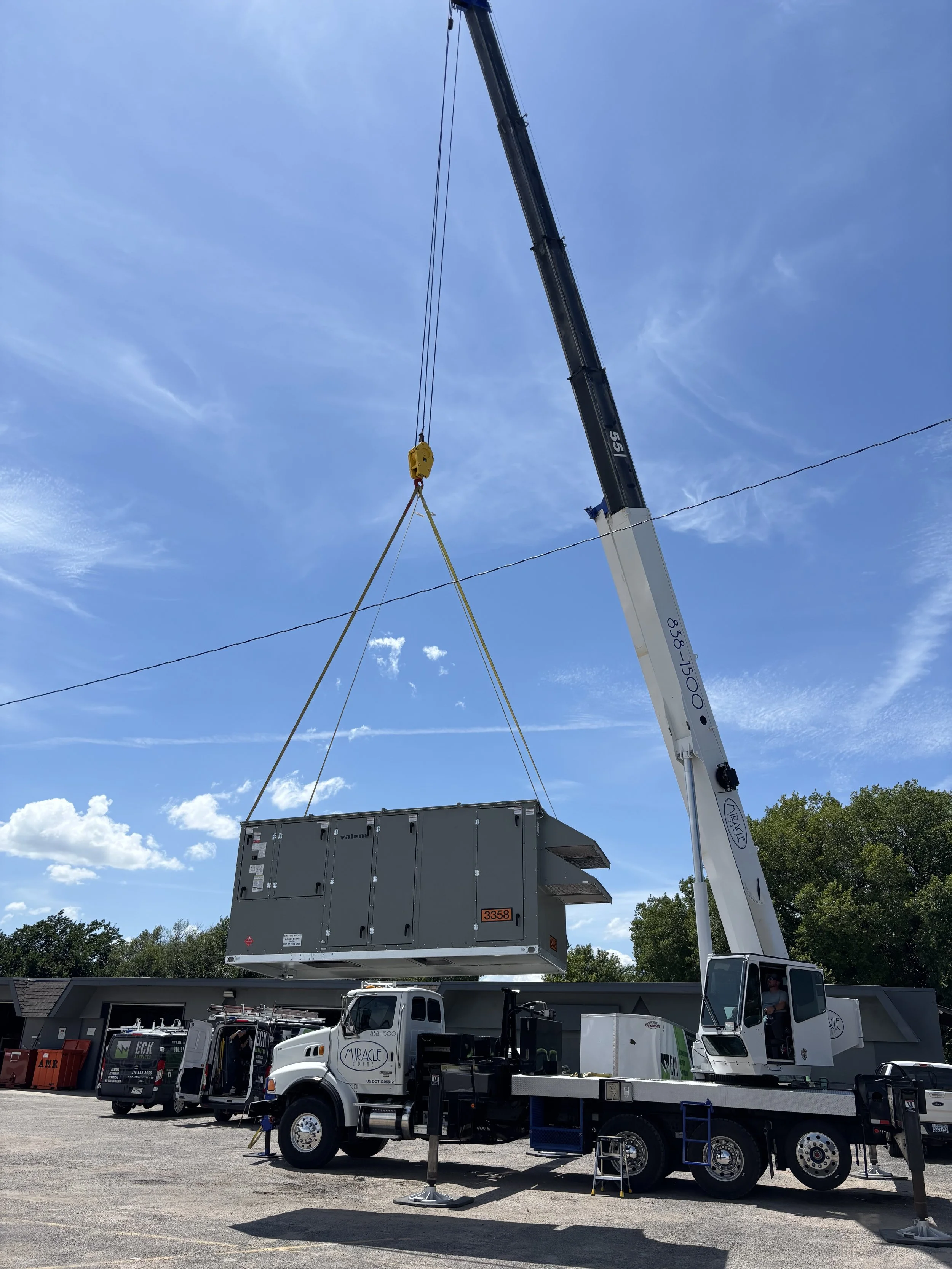 Miracle Crane lifting large rooftop HVAC unit with mobile crane at commercial job site in Wichita, Kansas