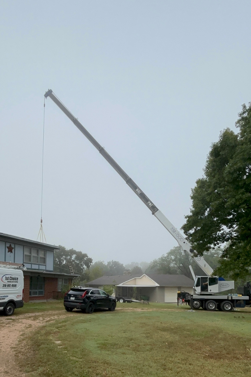 Mobile crane lifting rooftop HVAC unit onto residential home in Wichita Kansas