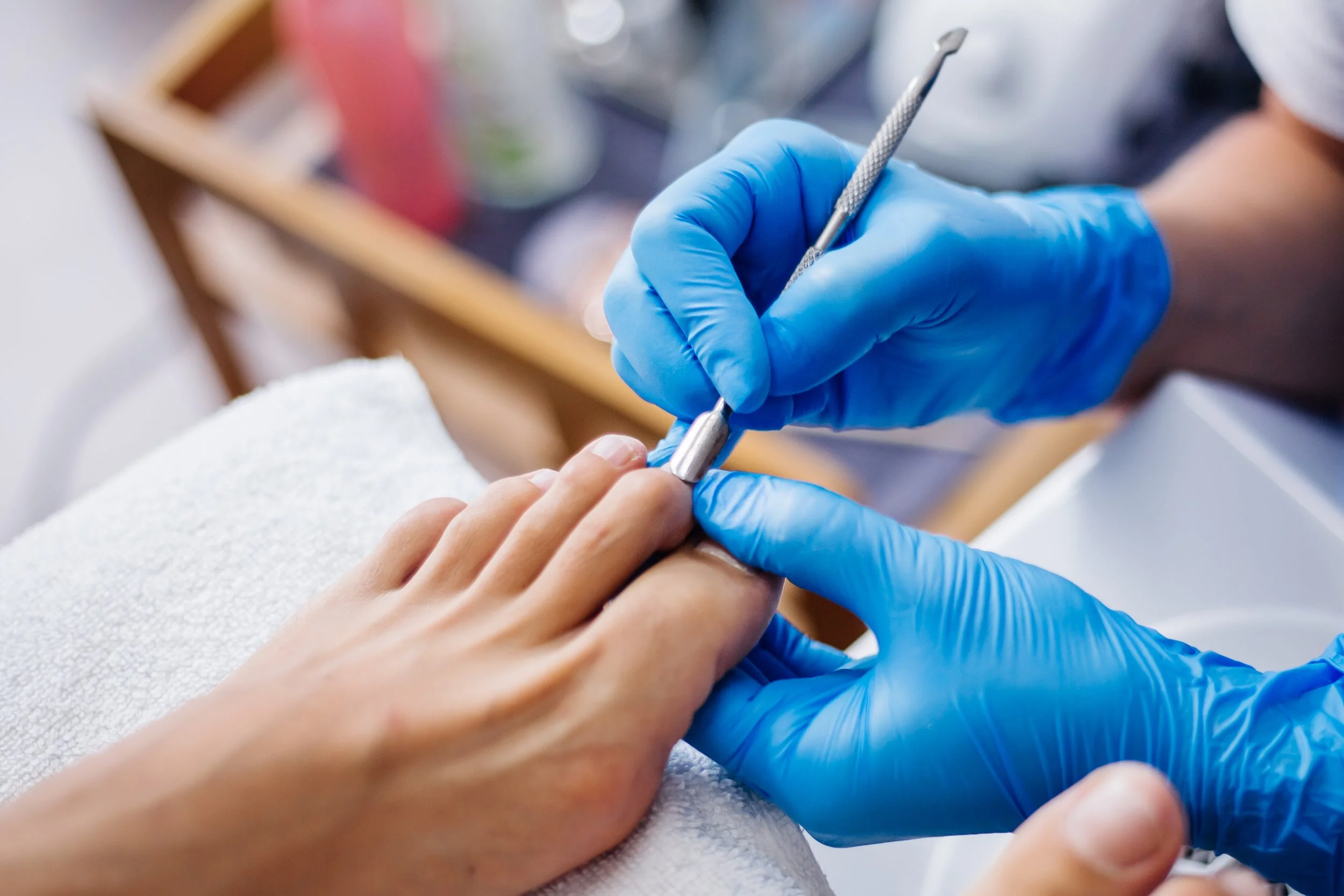 A person wearing blue gloves getting a manicure or nail treatment.