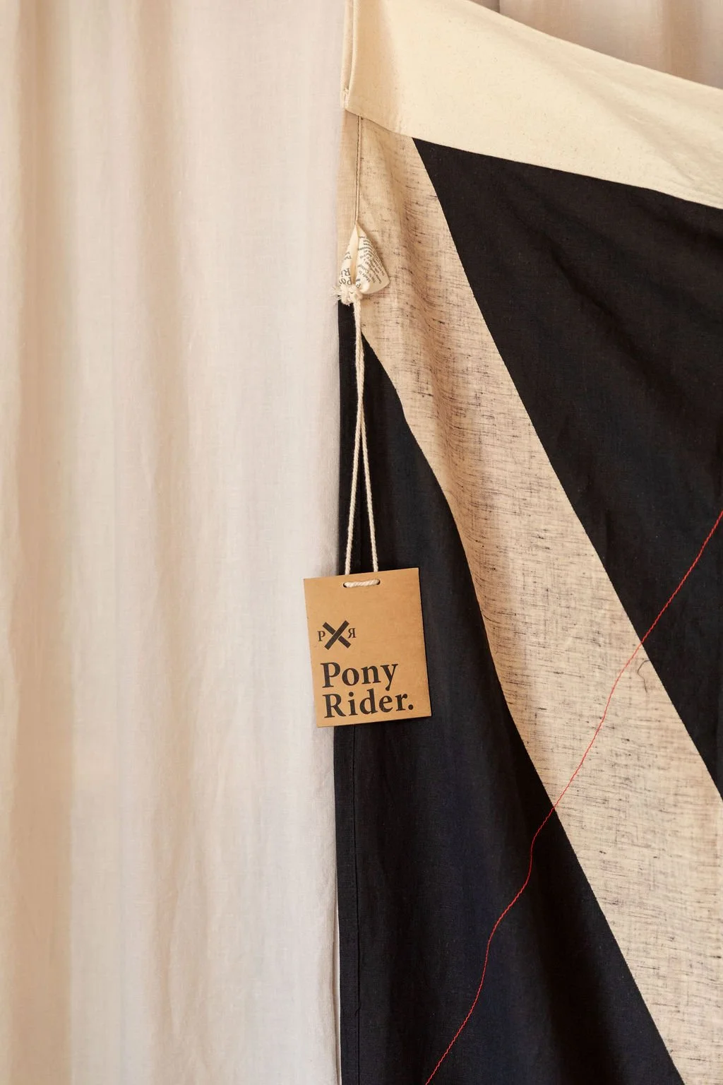 A fabric stall displays beige and black fabrics, with a Price Pony Rider tag hanging on one of the fabrics.