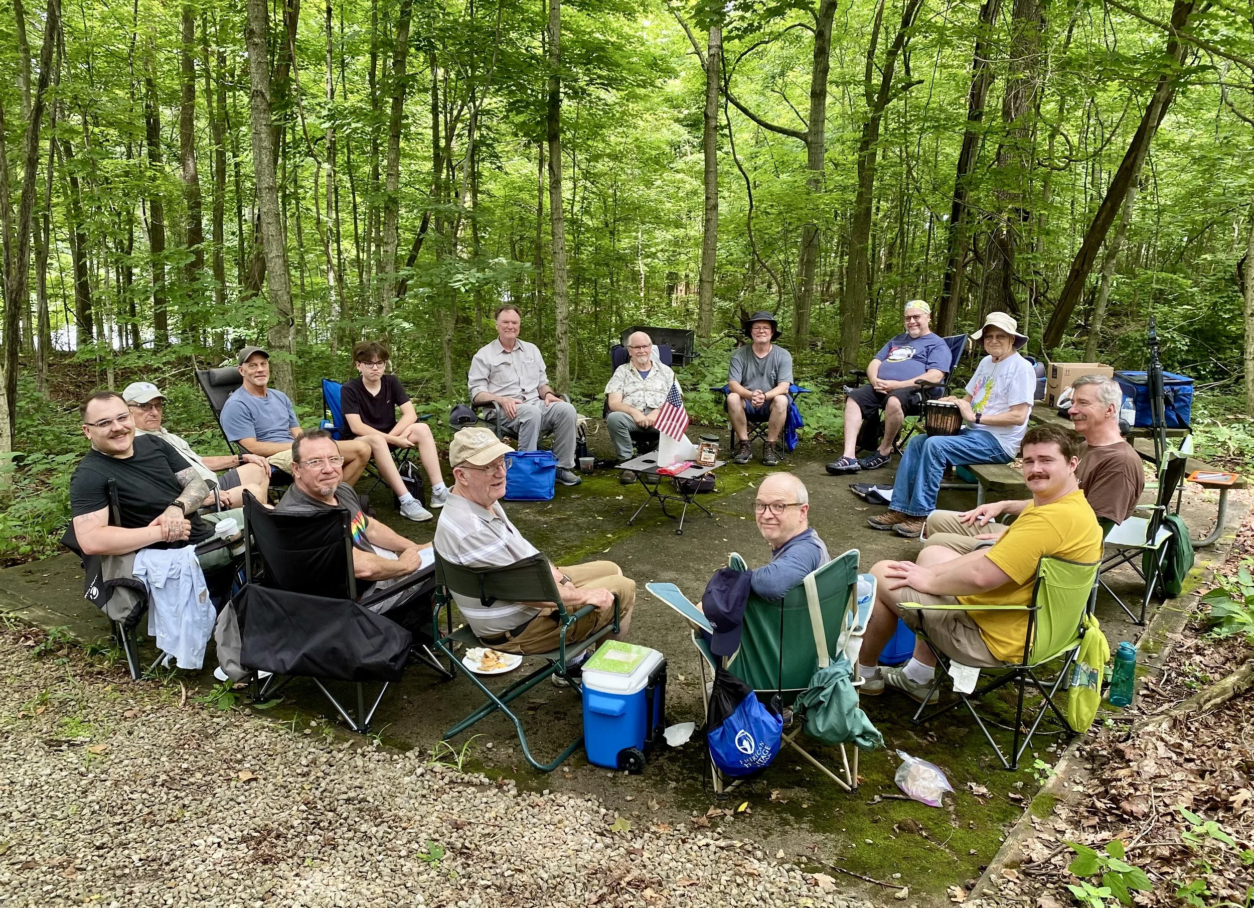 Men gathered in a circle of camp chairs in the woods for the closing circle at the 2025 Wandering