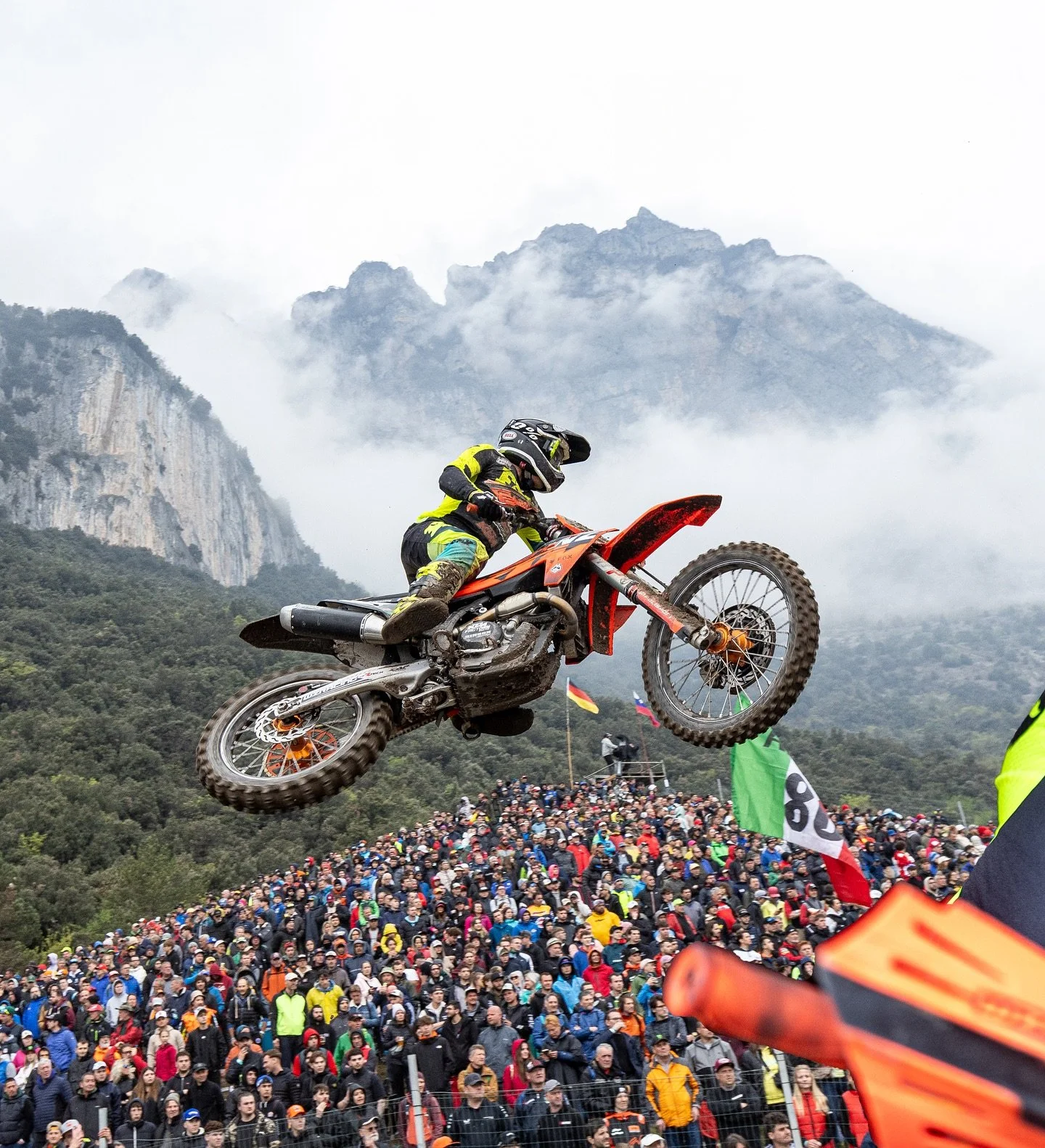 WZ Racing KTM rider jumping in front of a crowd, mountains in the background