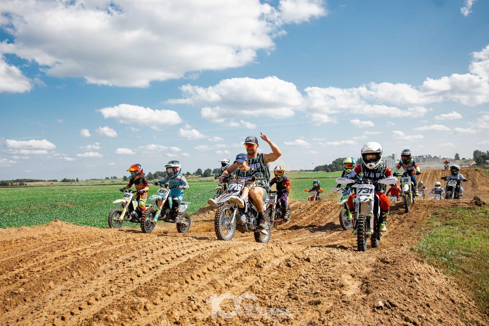 group of motocross kids taining group riders riding on offroad dirt track following trainer