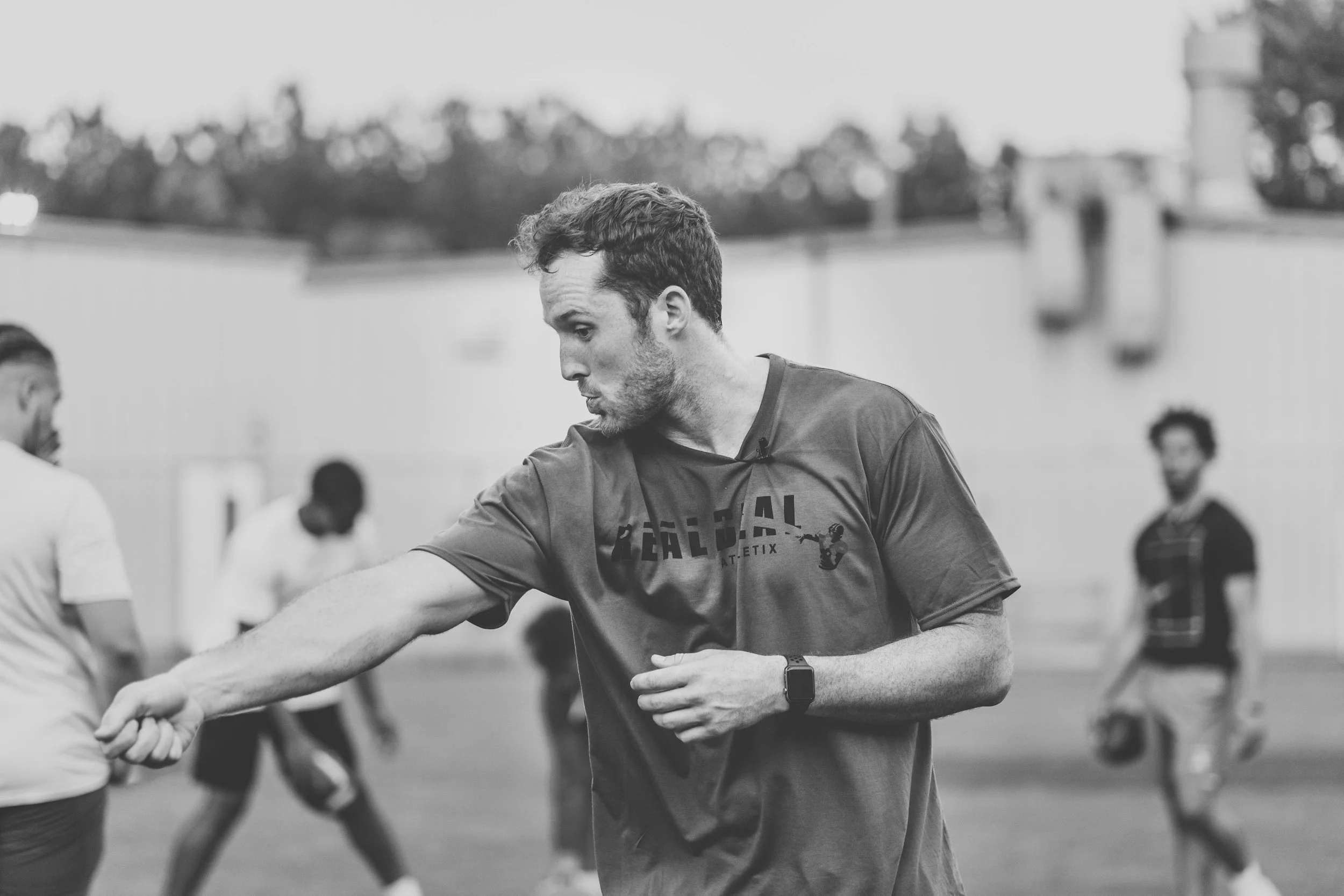 coach demonstrating a quarterback drill during athletic performance training, showcasing hands-on coaching and skill development at real deal athletix