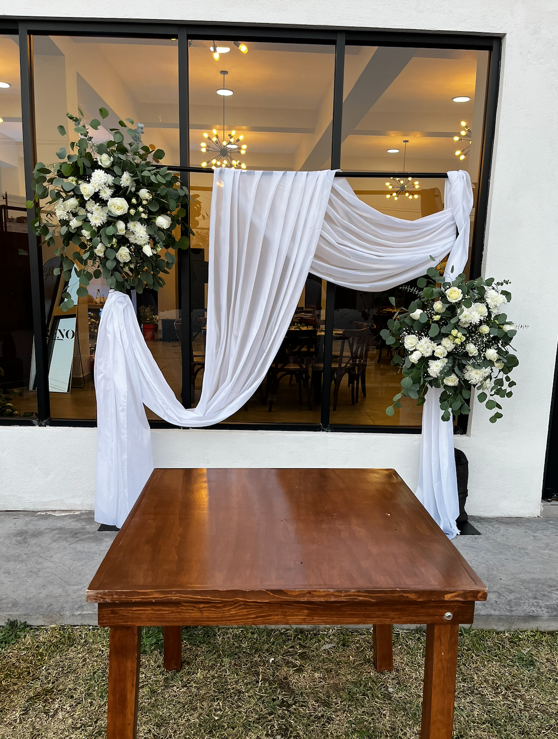 Backdrop floral para boda con cortinaje blanco, arreglos florales elegantes y mesa ceremonial, diseño realizado por Petalia en Ciudad Juárez
