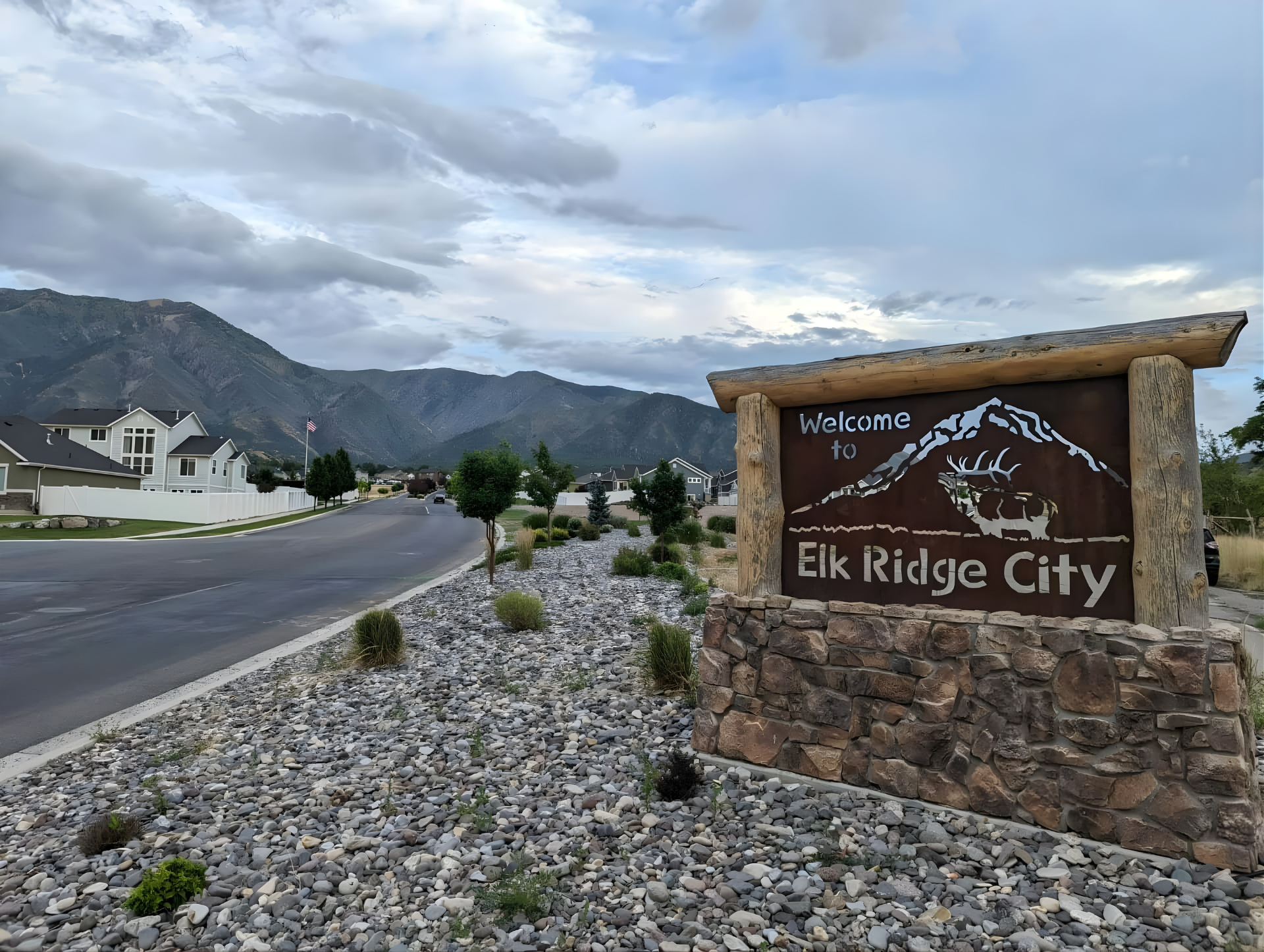 Welcome to Elk Ridge City sign with homes and mountains behind it