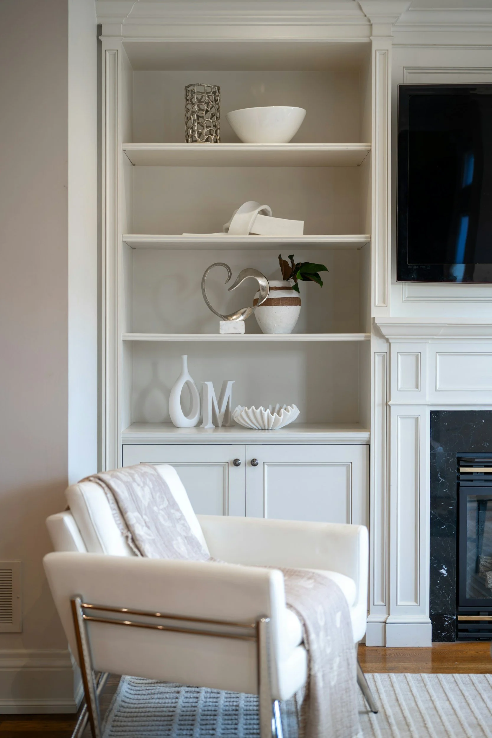 Built-in media wall cabinetry with display shelving beside a wall-mounted TV