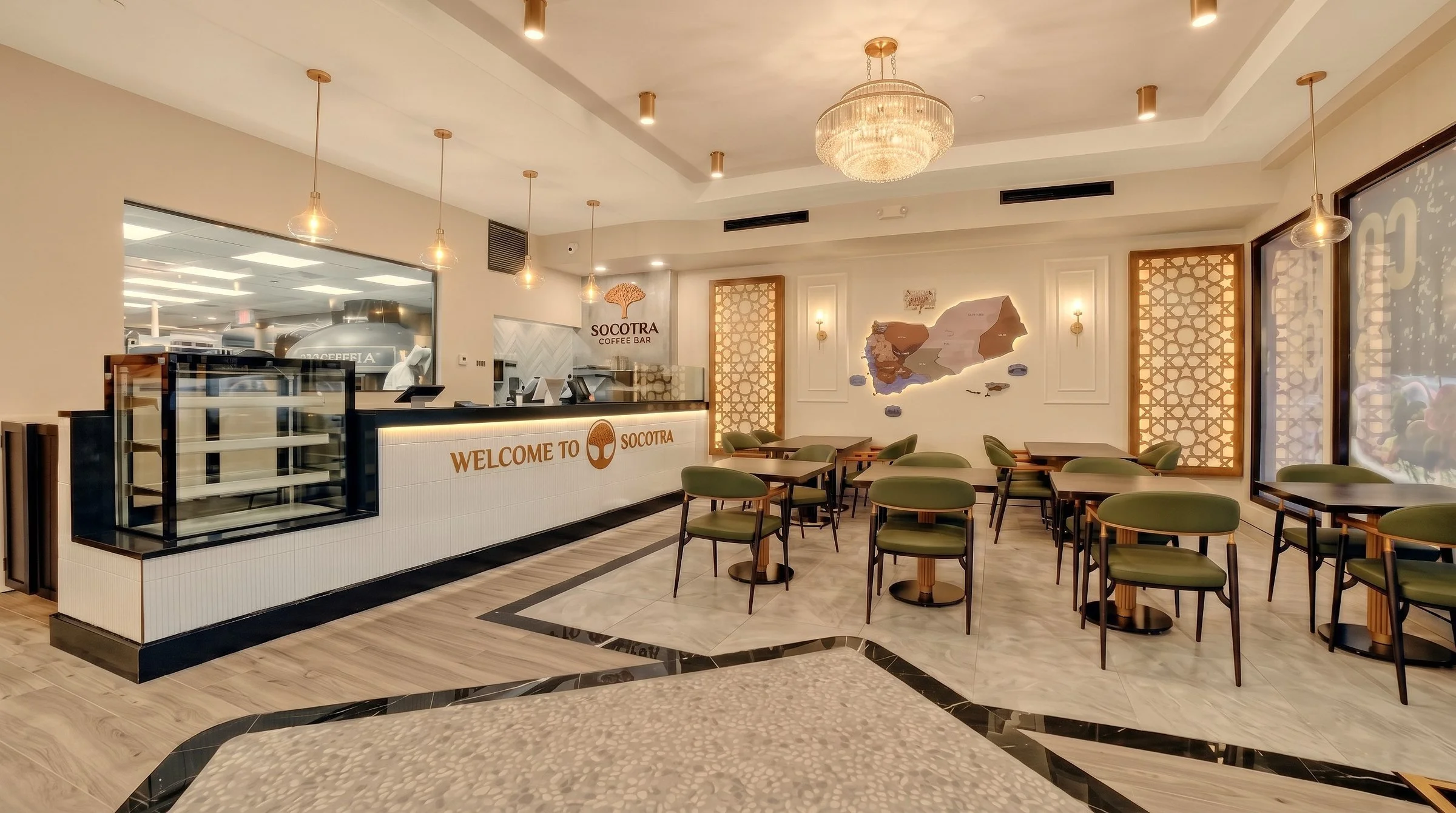 aSocotra Coffee Bar welcome counter with backlit logo, pastry display case and green dining chairs, Clifton NJ