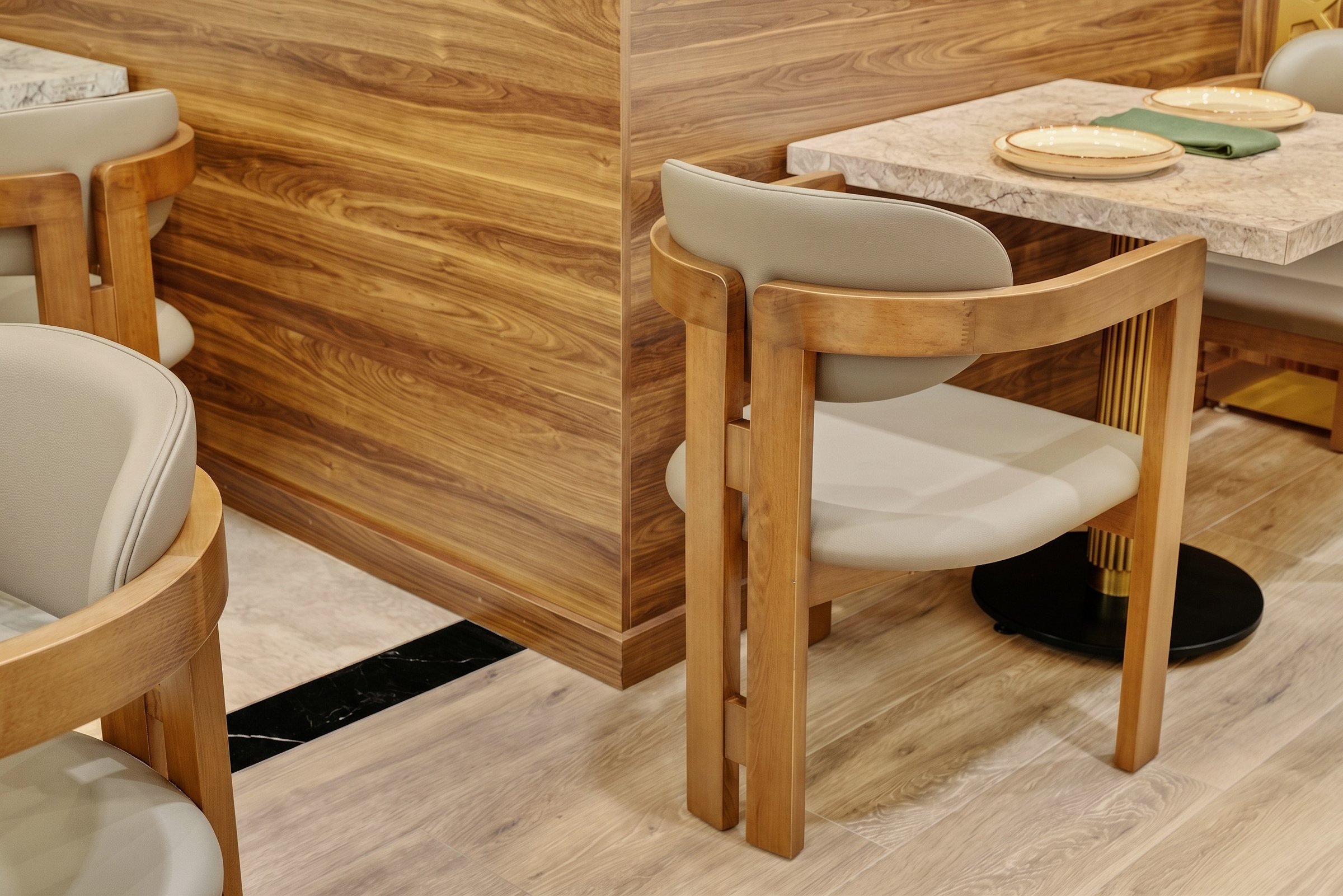 aCustom walnut-tone dining armchair and wood wall paneling detail at Socotra Restaurant, Clifton NJ