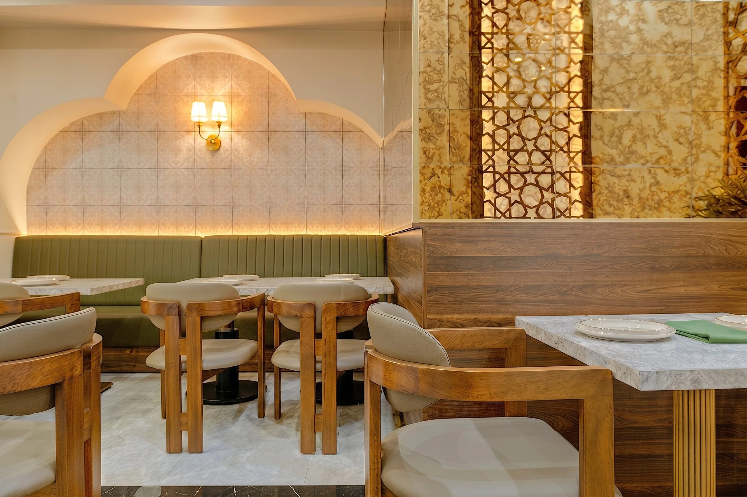 aGold mashrabiya lattice screen and walnut wall paneling beside arched banquette seating at Socotra Restaurant, Clifton NJ