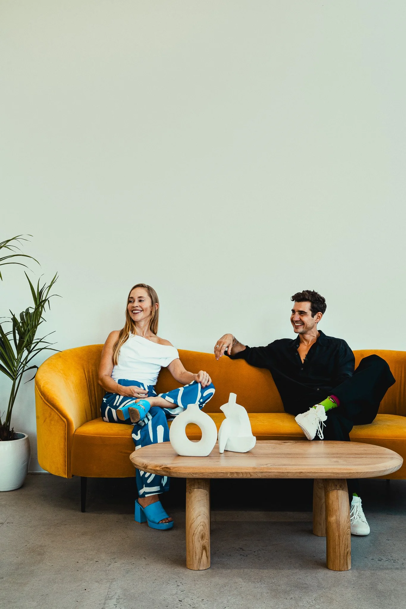 a Woman and a man seating on a yellow sofa located in the middle of the picture. 