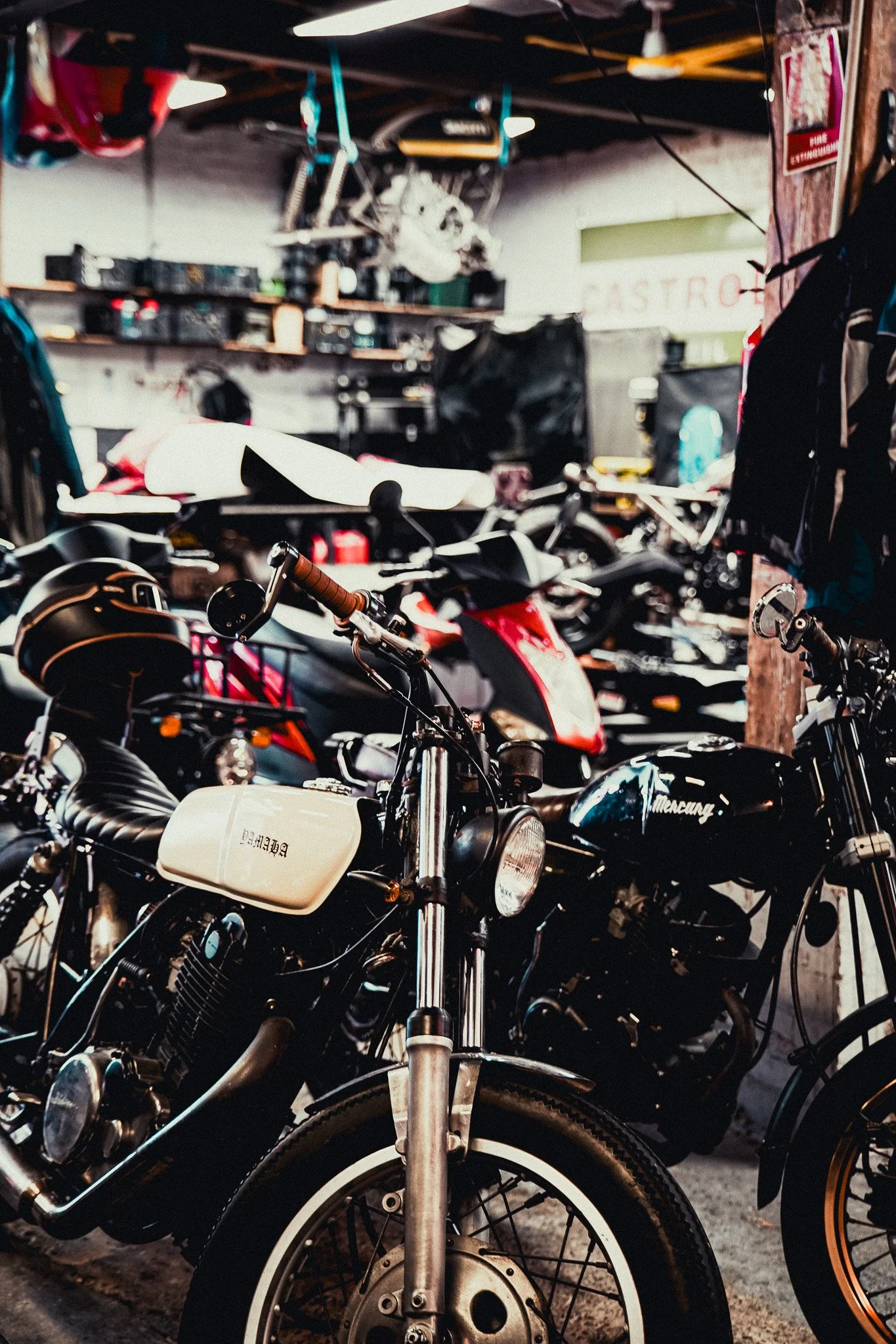 Indoor motorcycle shop with multiple bikes and helmets, featuring a vintage black and white motorcycle in the foreground.