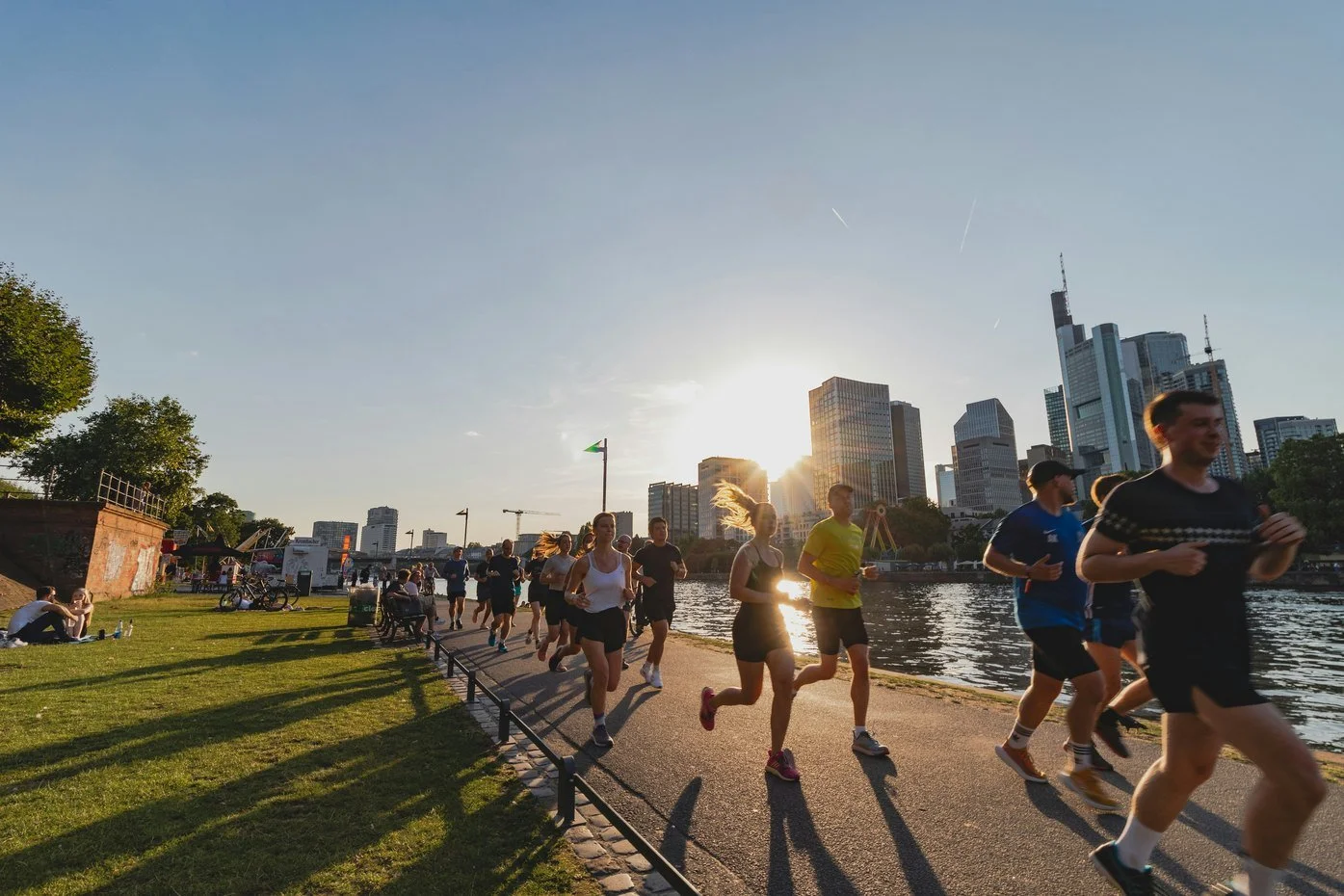 A weekly running group jogs together along a riverside path at sunset