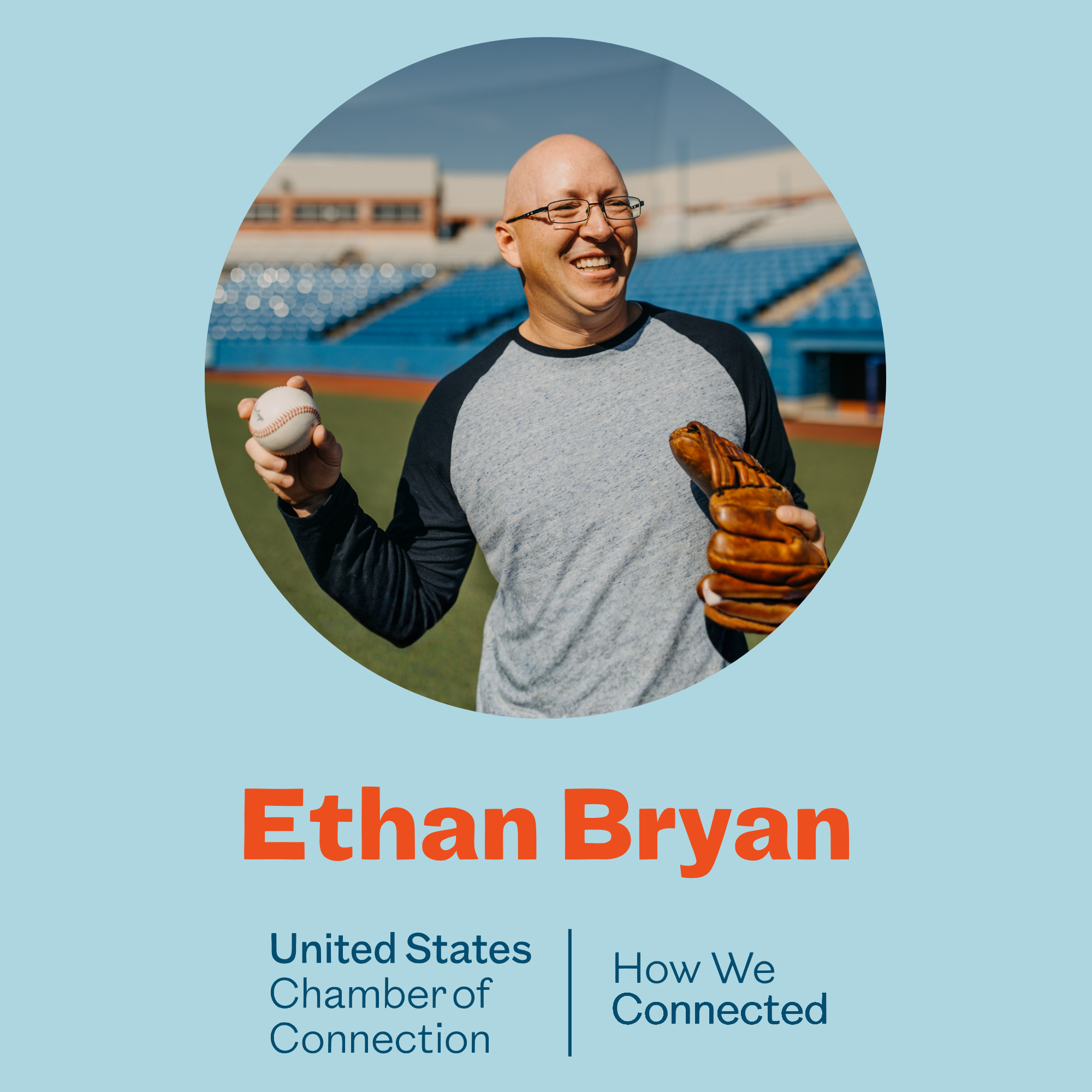 A man with glasses smiling, holding a baseball in his right hand and a baseball glove on his left hand, standing on a sports field with empty blue bleachers in the background during daytime.