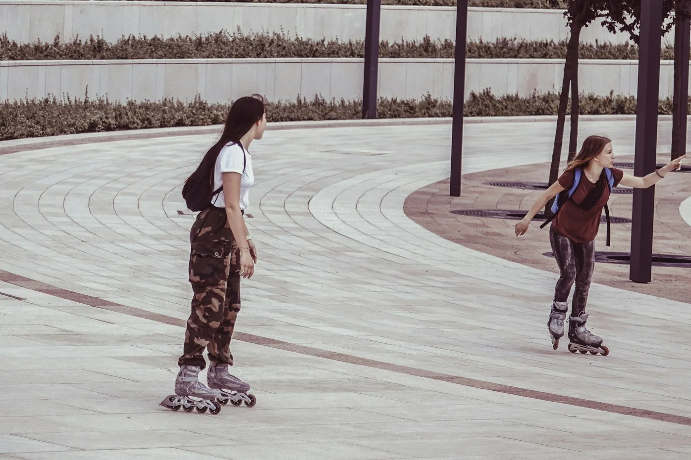 Two friends inline skating together across a curved plaza, the kind of weekly activity that builds social health