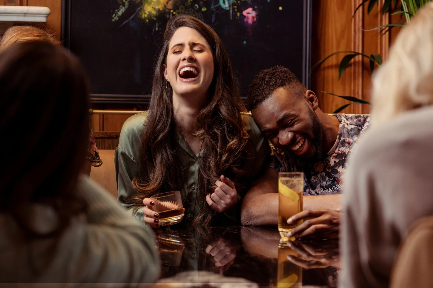 Dinner guests laughing together around a table at a gathering