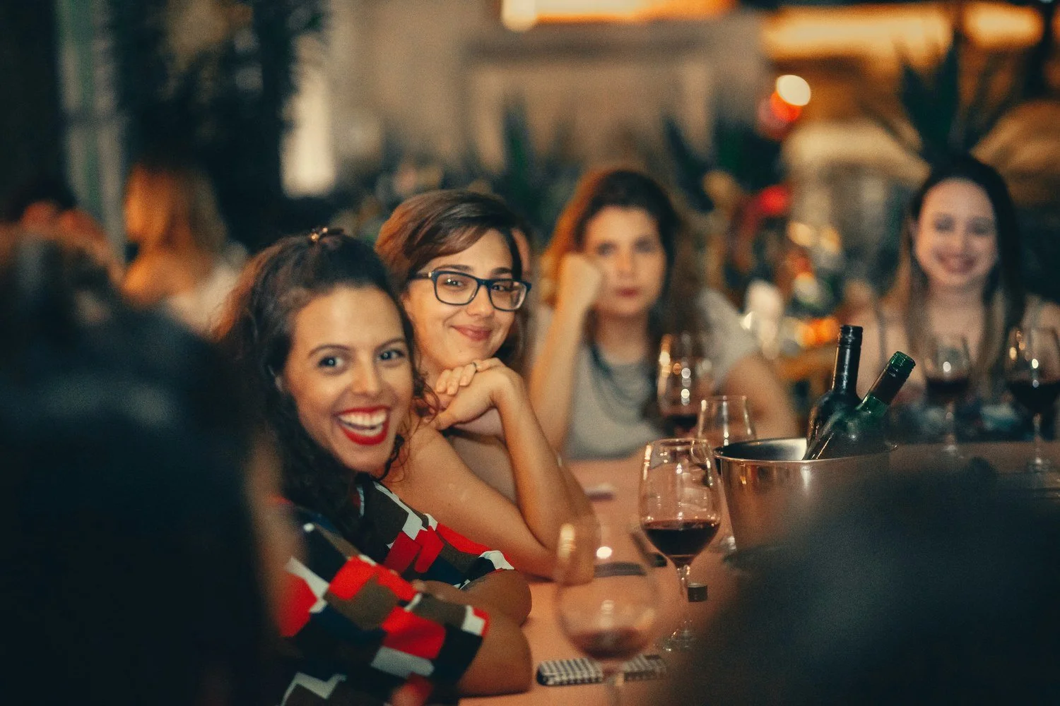 Three women smiling and talking together at a restaurant table