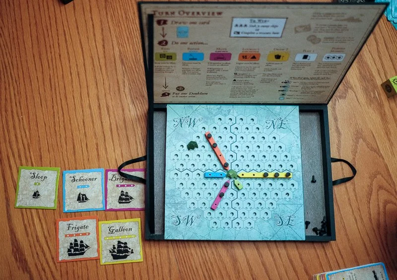 July 2024. Our current working prototype! A turn overview on the underside of each game chest helps players learn and follow the rules.