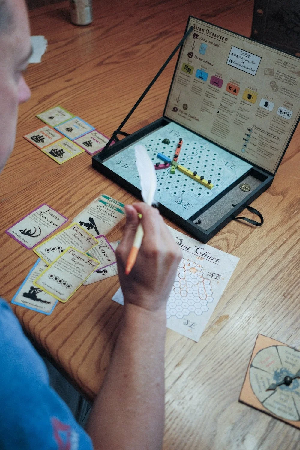 A man is seated at a table, planning his next move on a fun board game laid out in front to him.
