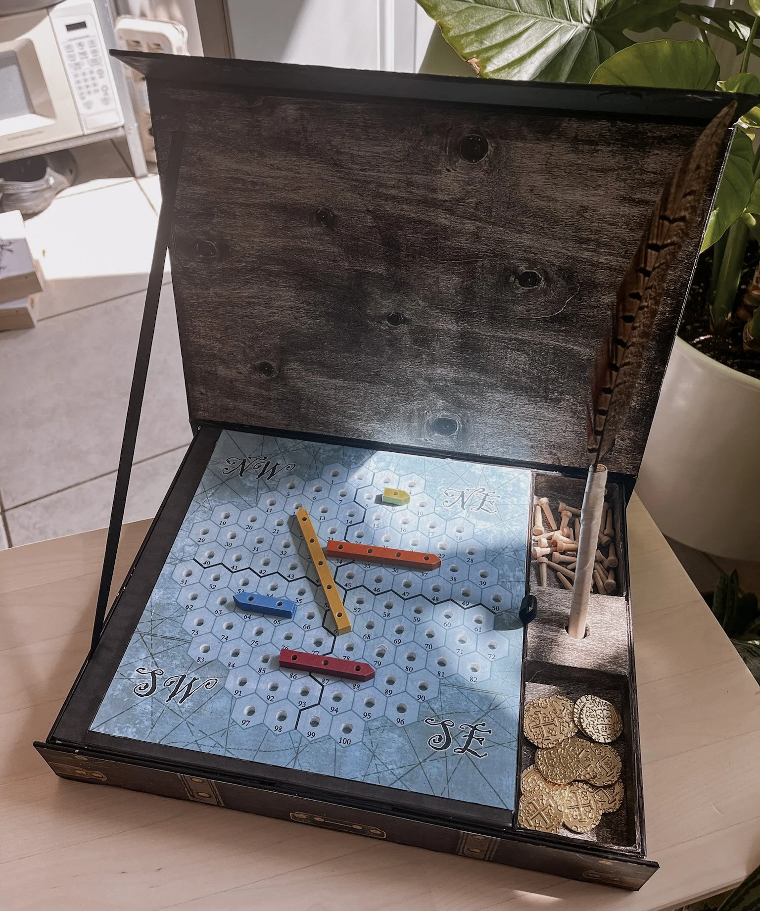 April 2023. In this version, we added holes for the ships to lock into the grid, metal coins, and quill pens.