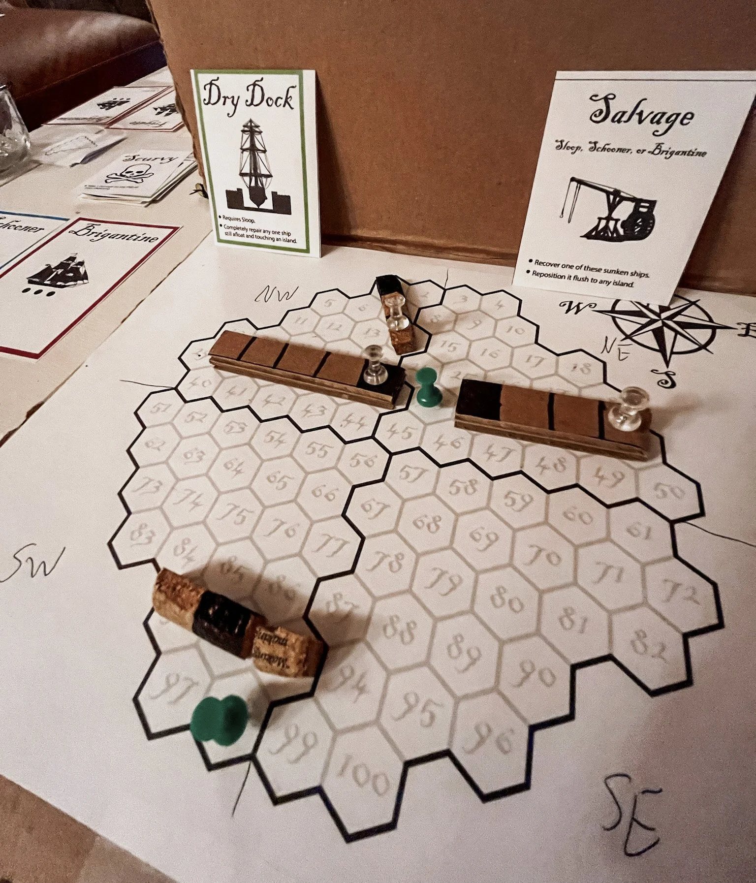 September 2022. Our first crude prototype. Note the hexagonal spaces, and ships made from pieces of cardboard and cork!