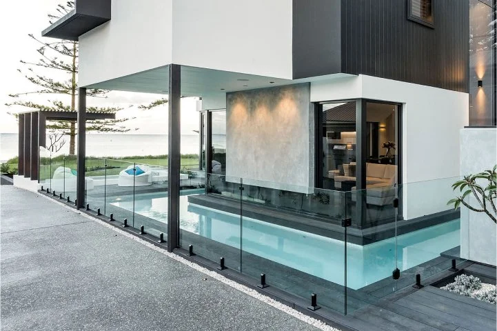 Modern house with glass enclosed swimming pool and outdoor seating area.