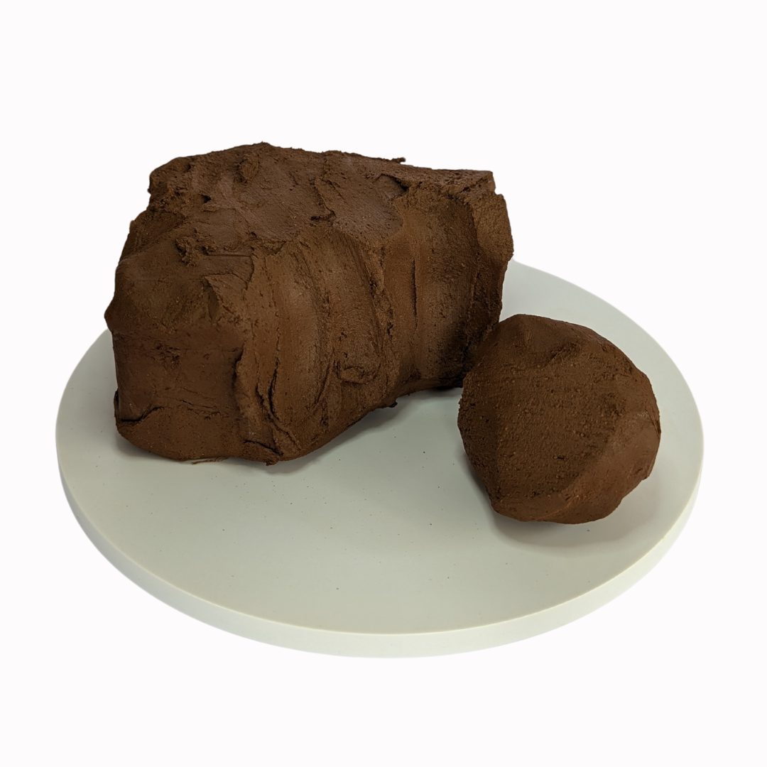 block of raw, chocolate brown clay with a section removed and made into a ball.
