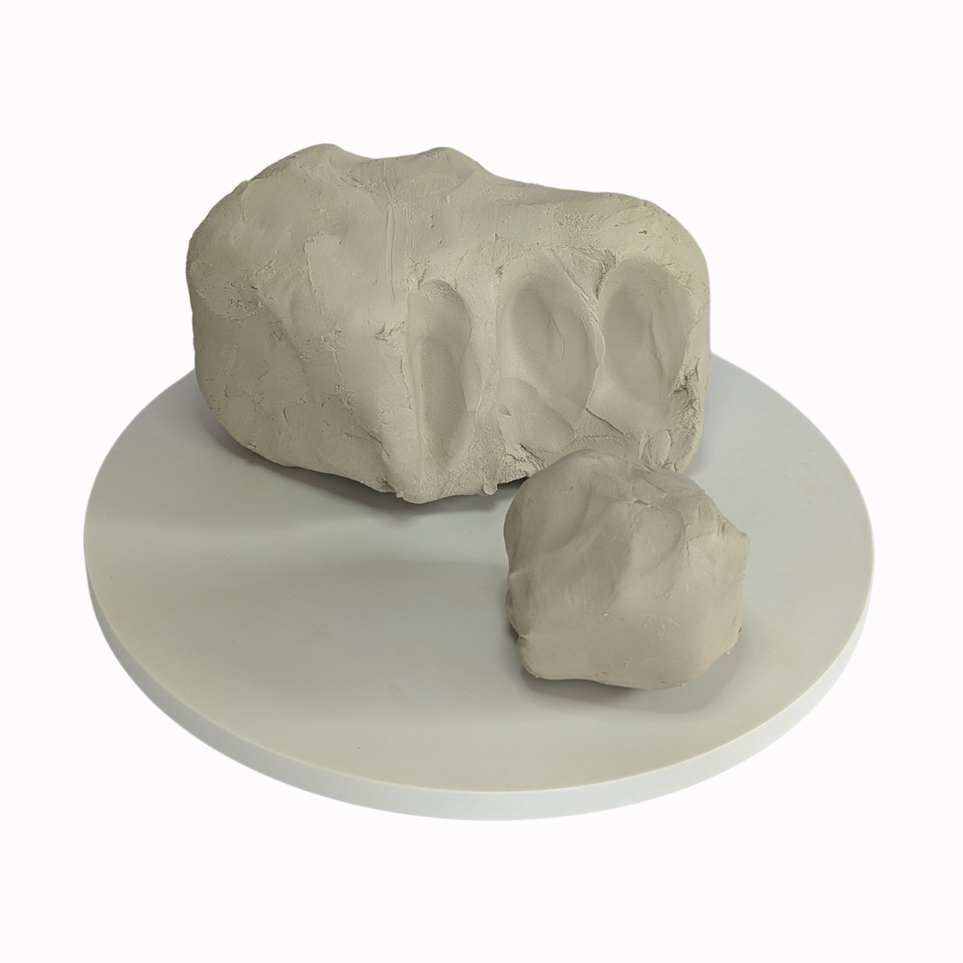 block of raw, white clay with a section removed and made into a ball.