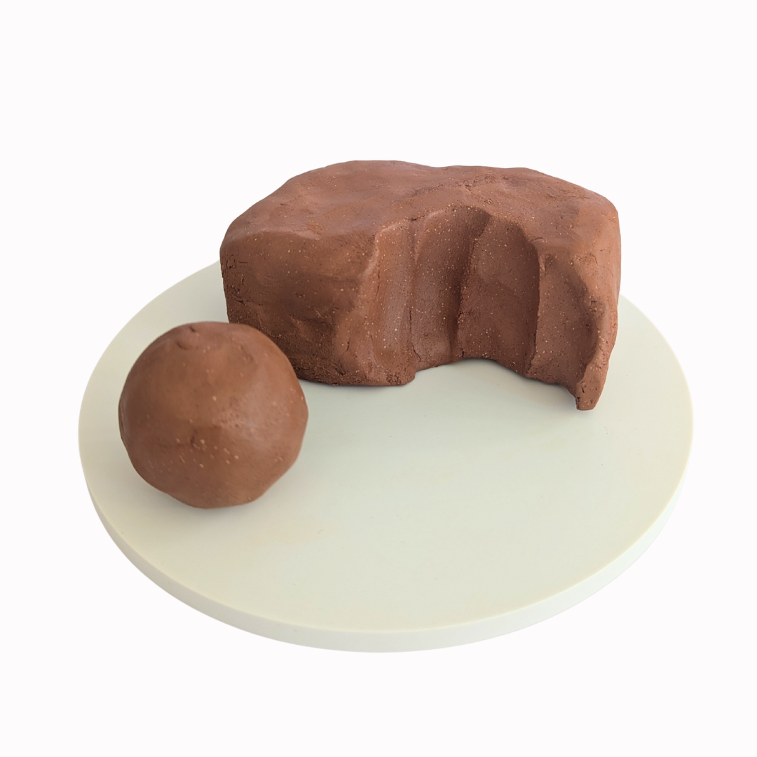 block of raw, deep orange clay with white speckles.