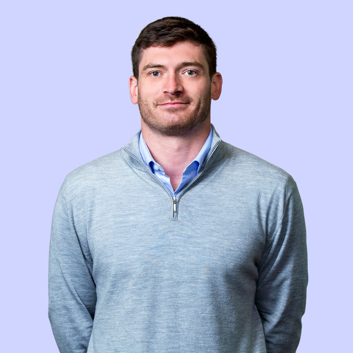 Gareth wearing a red sweater, smiling against an orange background.