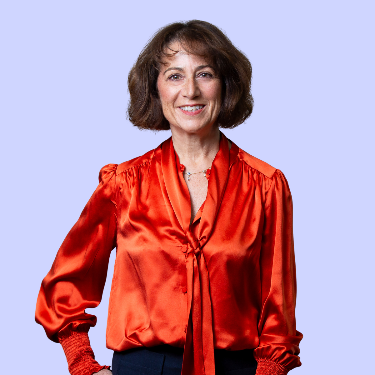 Debra smiling wearing a blue and white striped shirt against a plain background.
